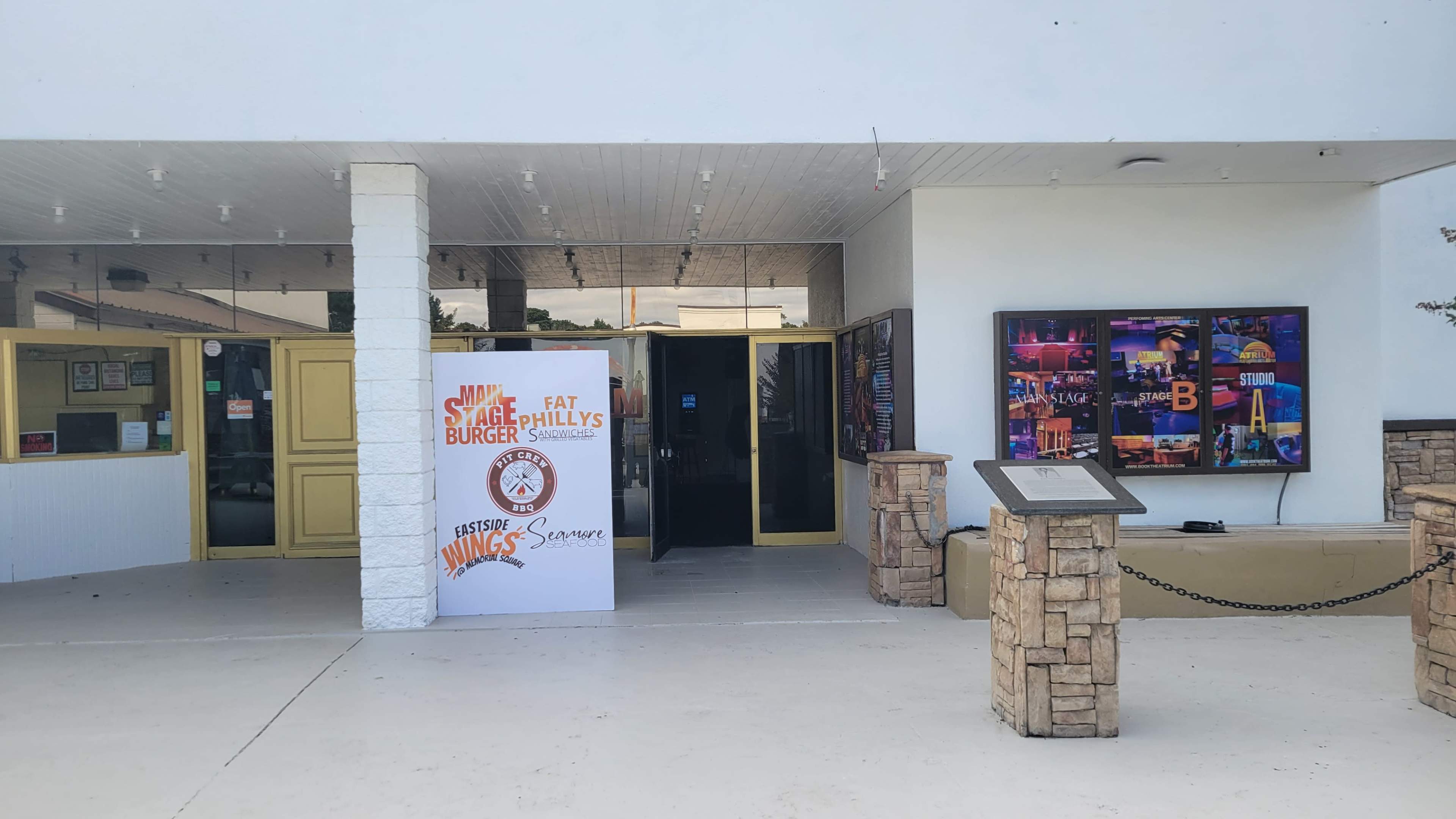 The entrance of a restaurant features a large sign for "Fat Philly's Burger" and a digital display with colorful images on the wall.