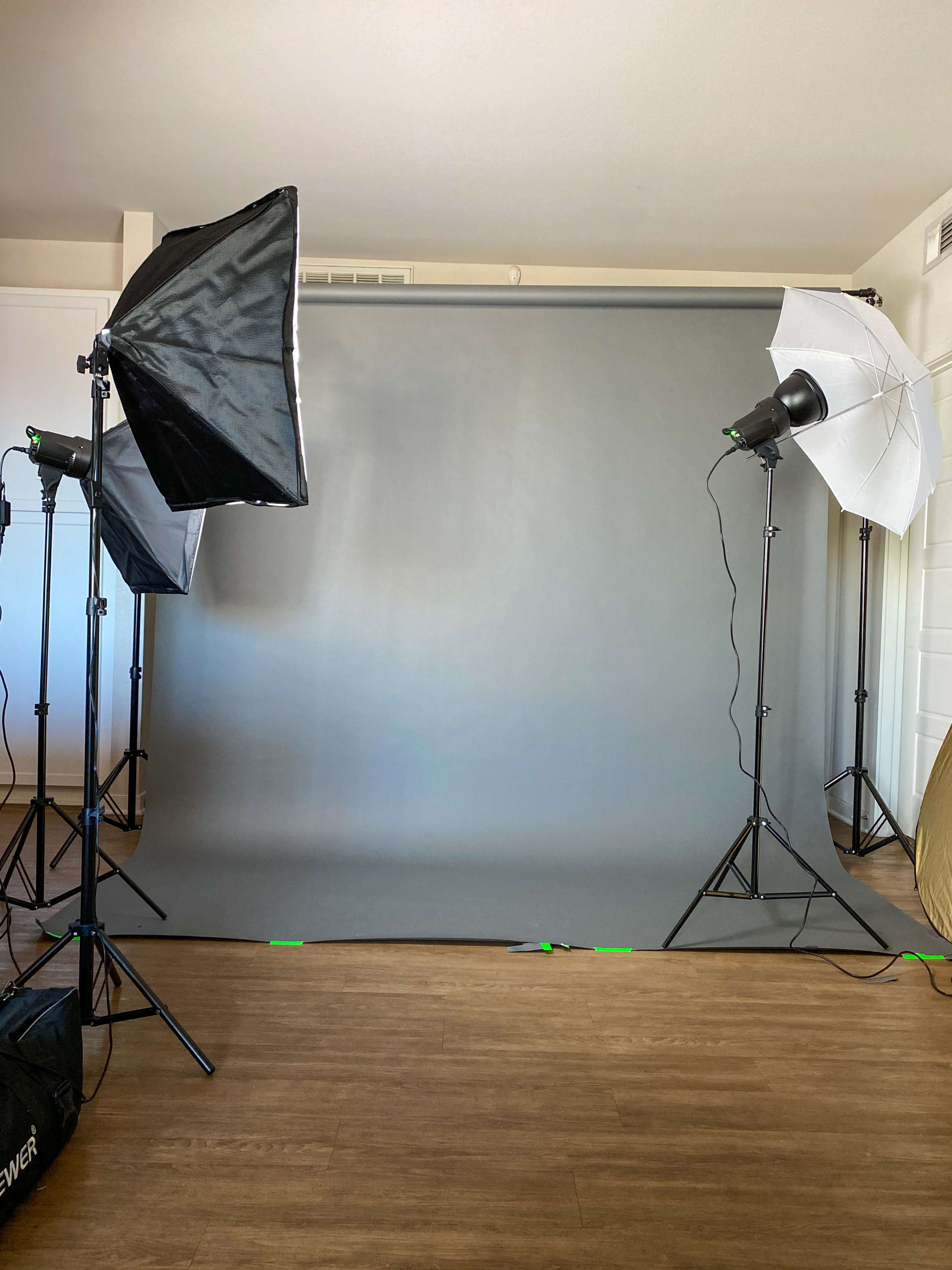 A photography studio setup with a gray backdrop and lighting equipment on either side.