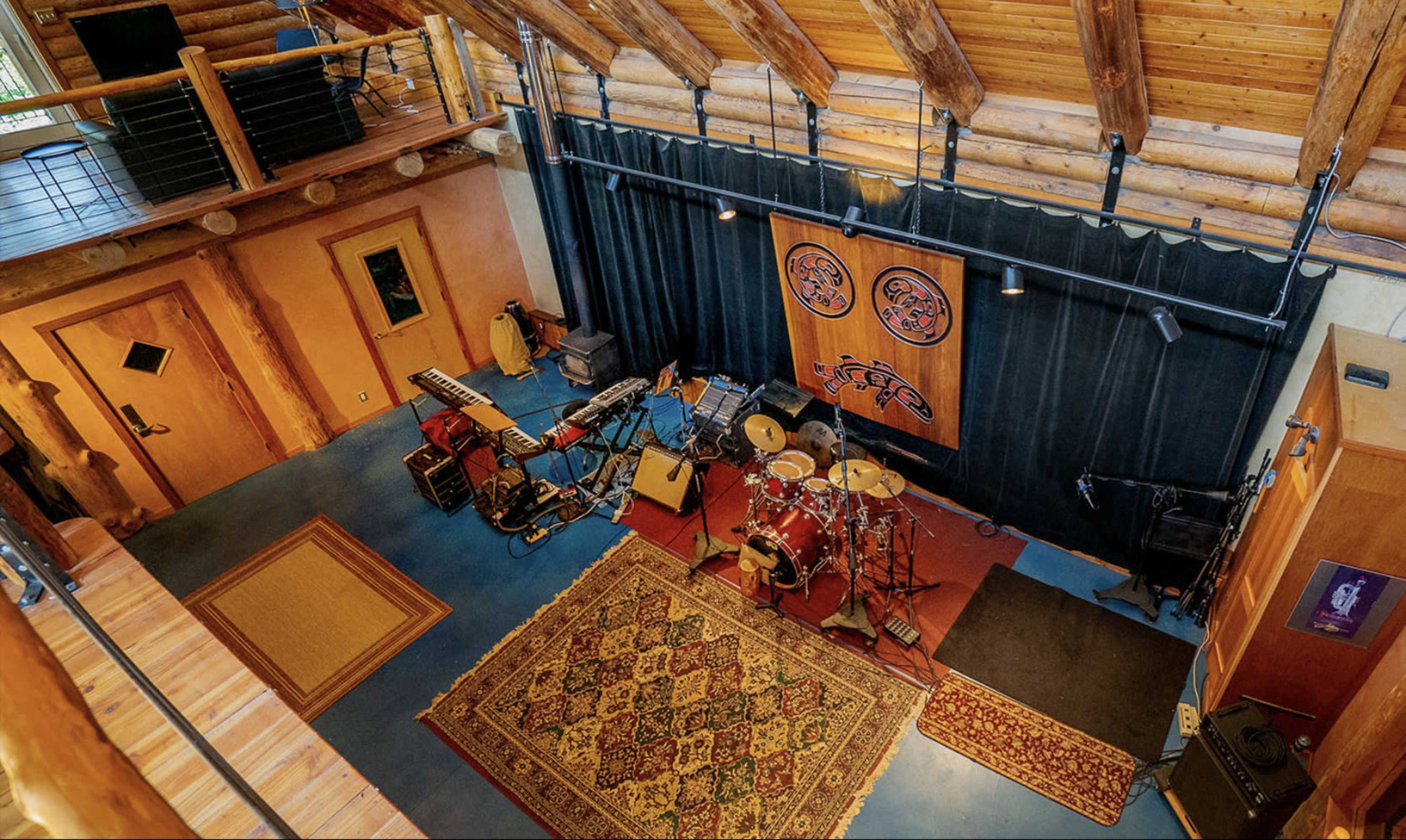 A music performance space with a stage, instruments, and a patterned rug beneath a wooden ceiling.