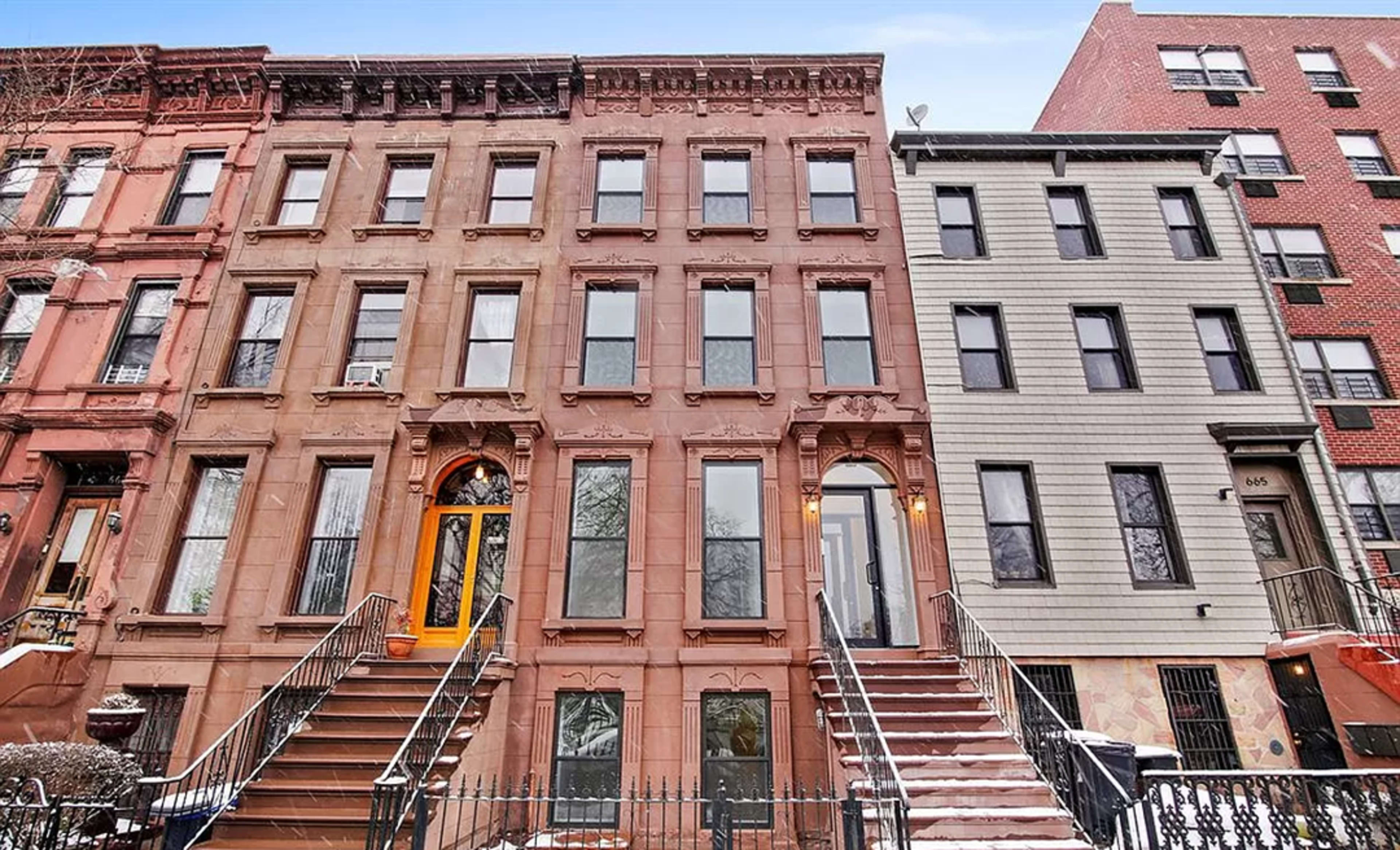 The image shows a row of three multi-story residential buildings with distinct architectural styles, including brownstone facades and a modern exterior, set against a clear sky.