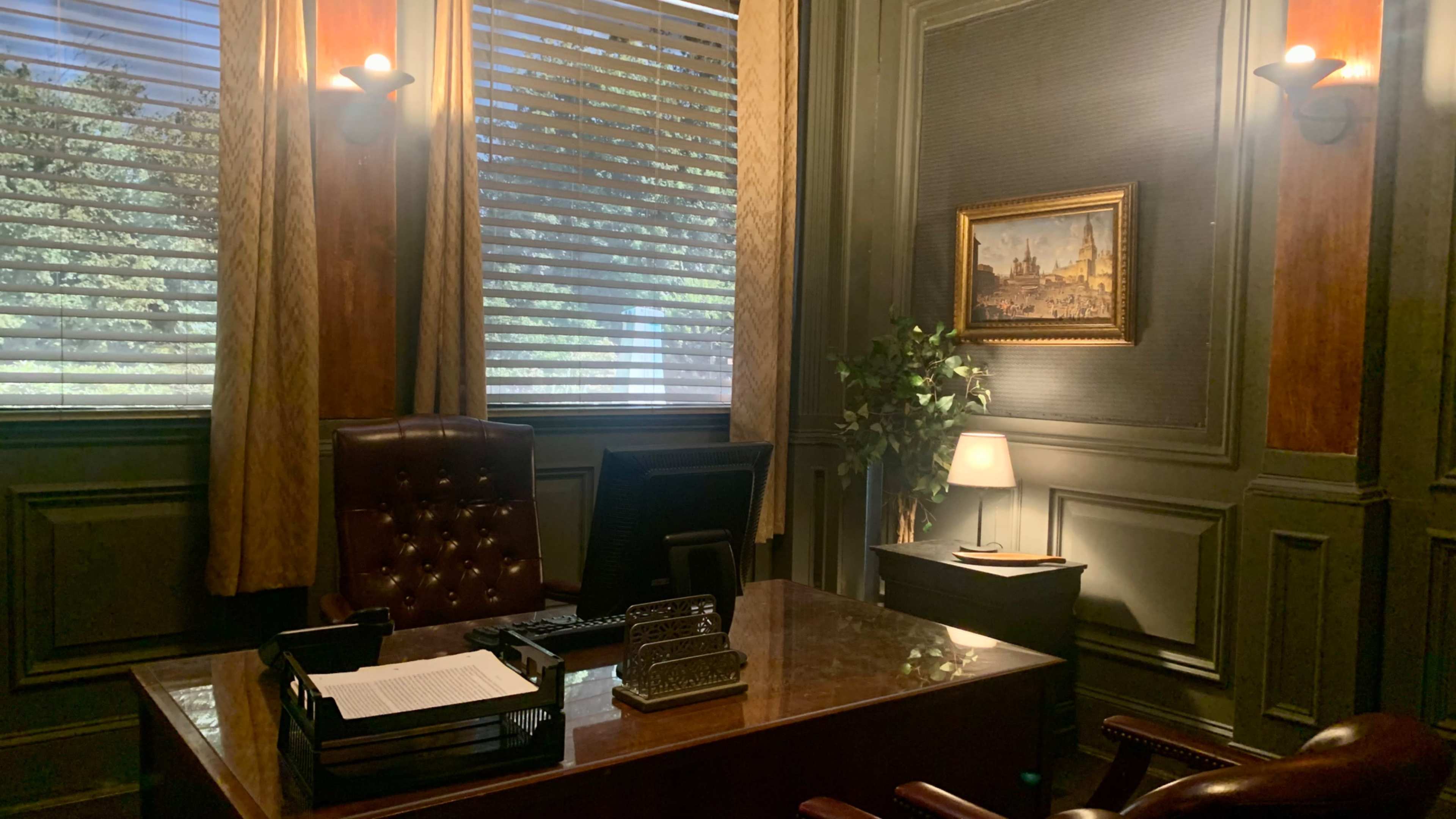 A well-furnished office with a wooden desk, a computer, a chair, and a decorative painting on the wall.