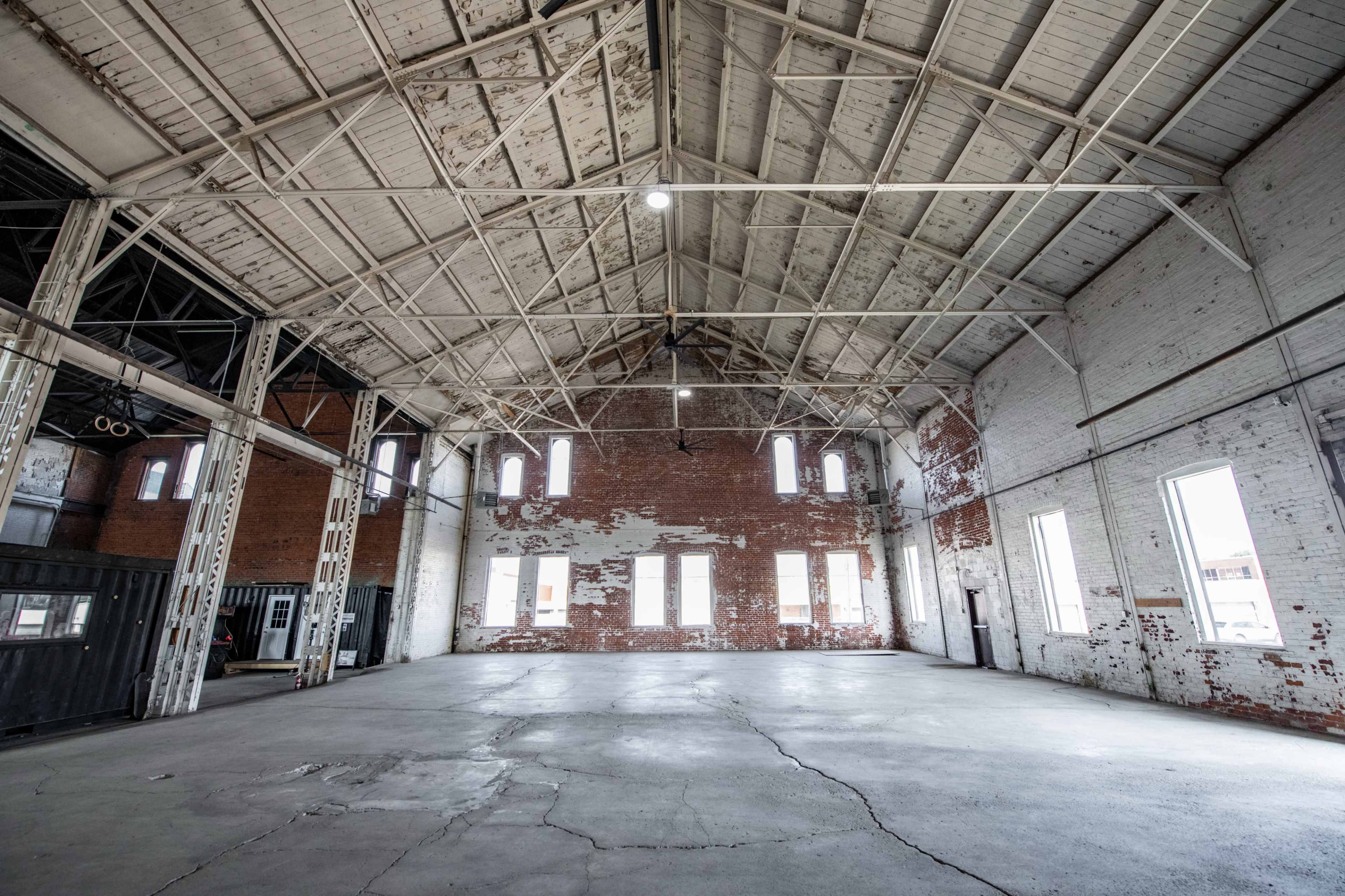 A large, empty industrial space with brick walls and high, exposed rafters.