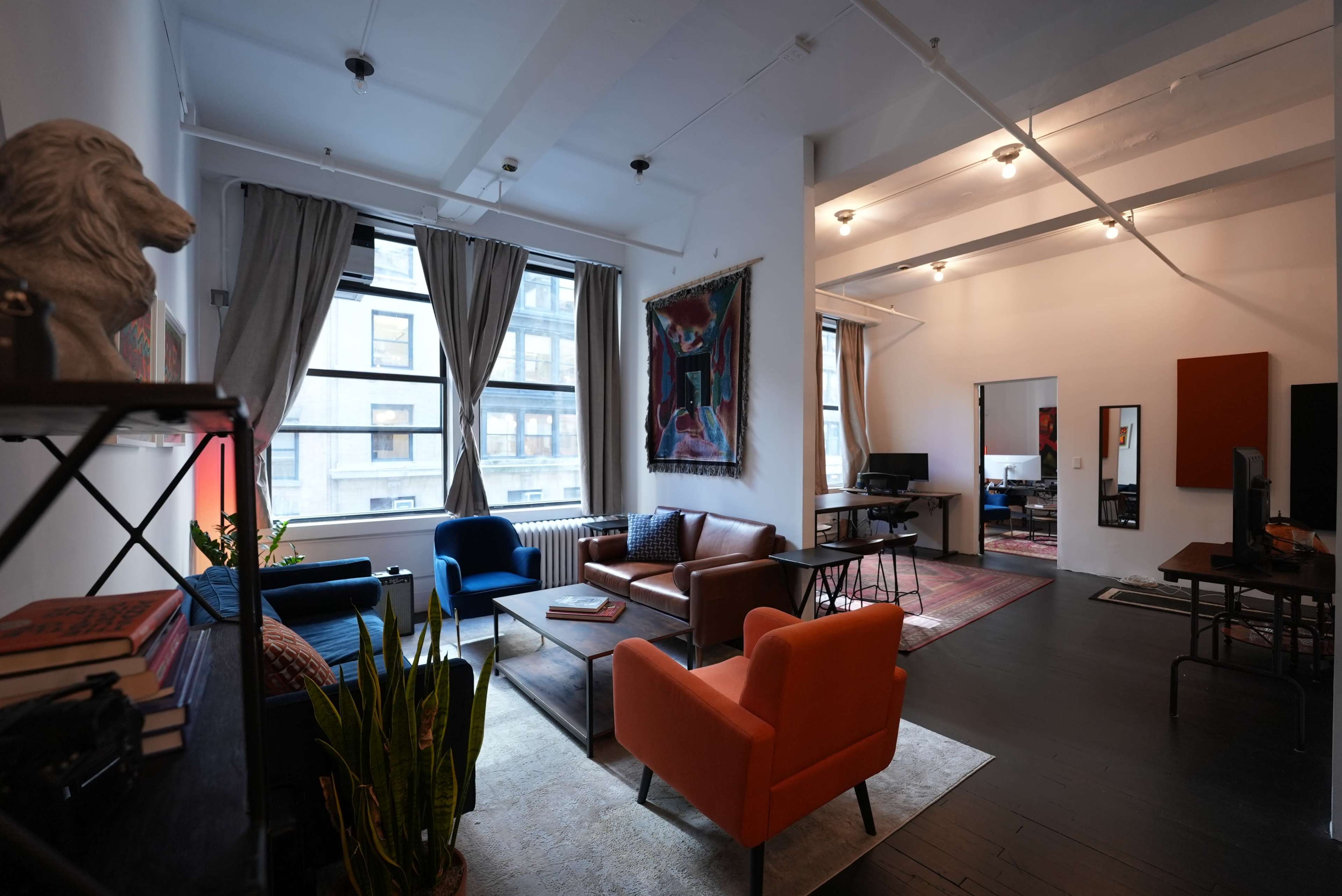 A modern living space featuring a mix of seating arrangements, large windows, and artistic decor.