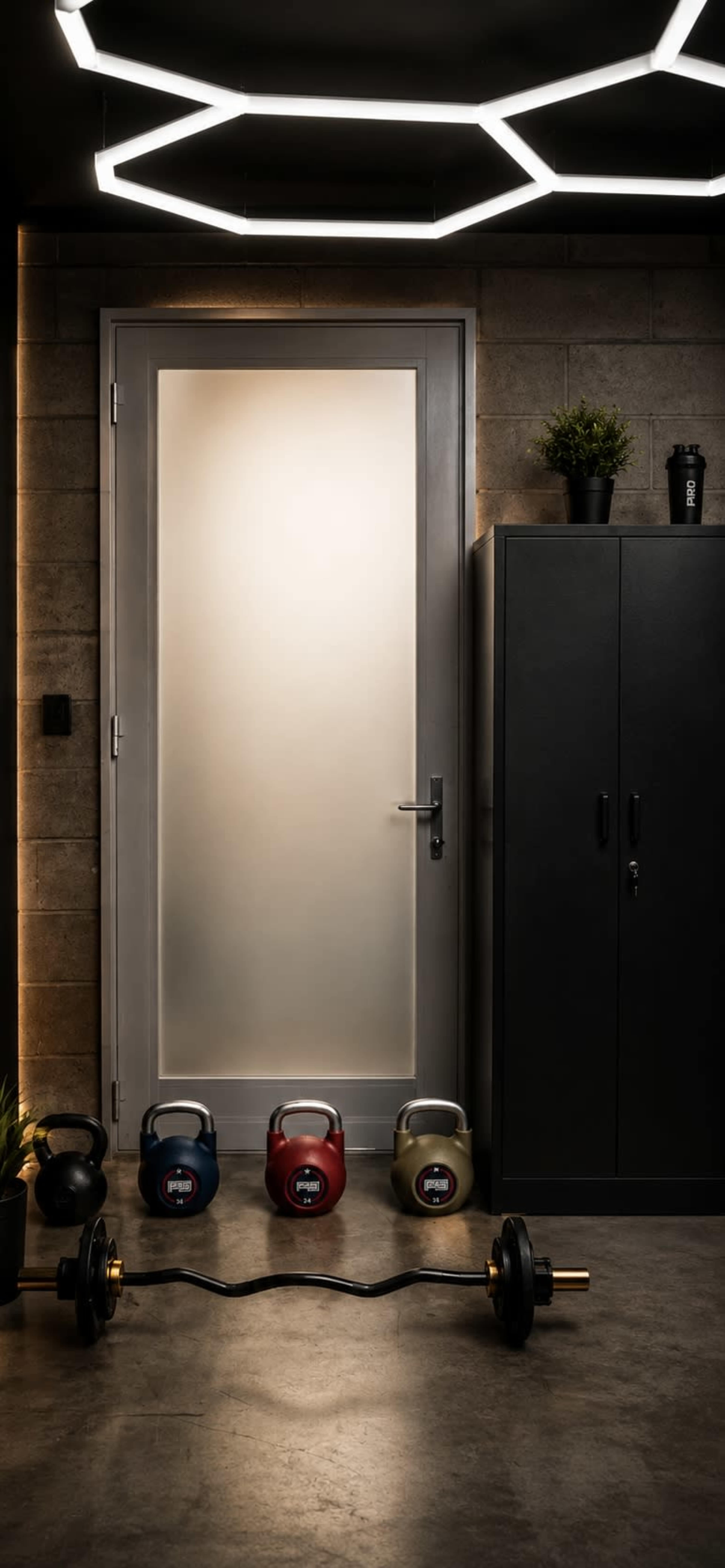The image features a modern gym space with a frosted glass door, a dark storage cabinet, and a collection of kettlebells and a barbell placed on the floor.