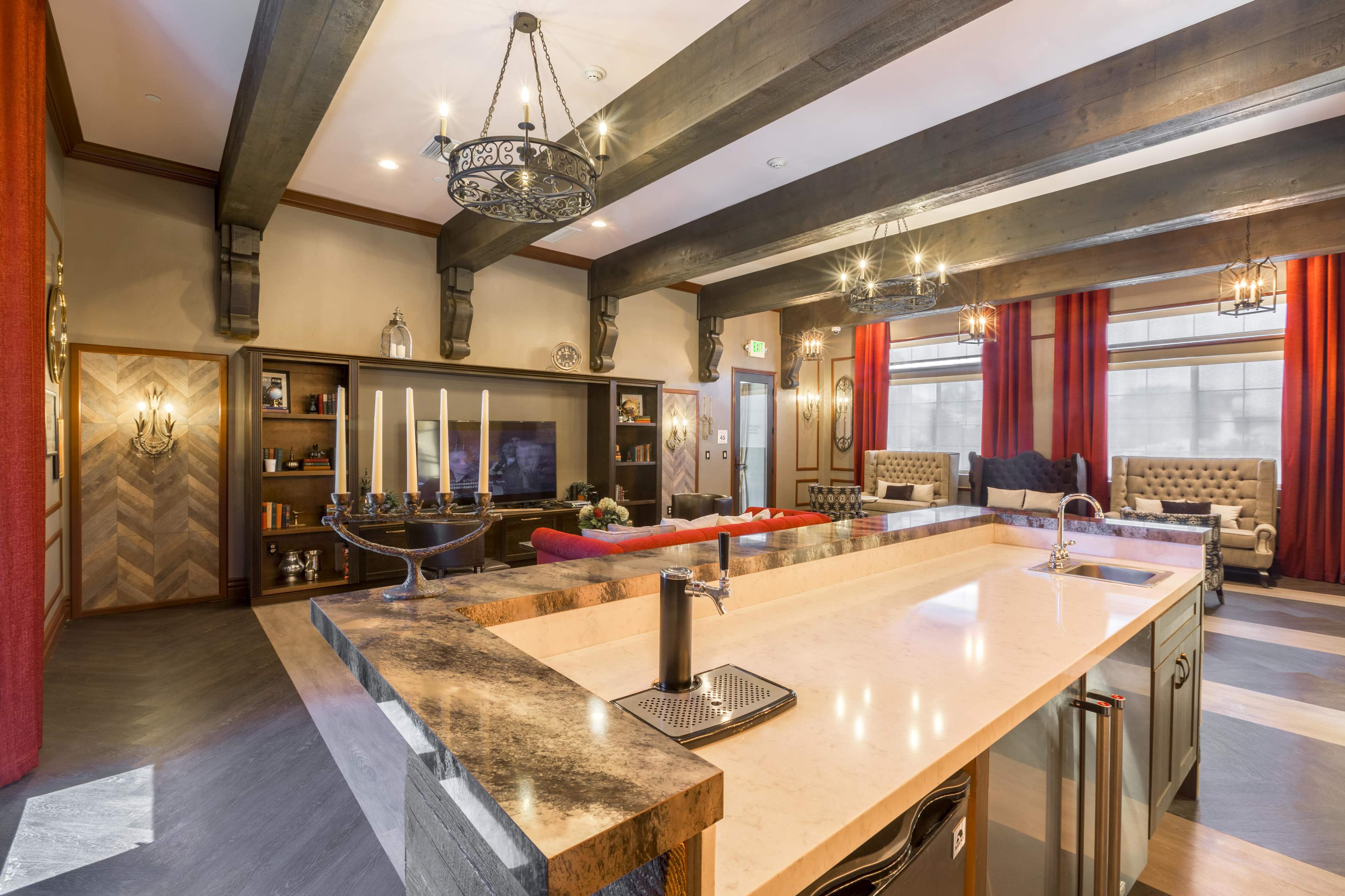The image shows a modern kitchen and living area with a large island, leather sofas, and decorative lighting fixtures.