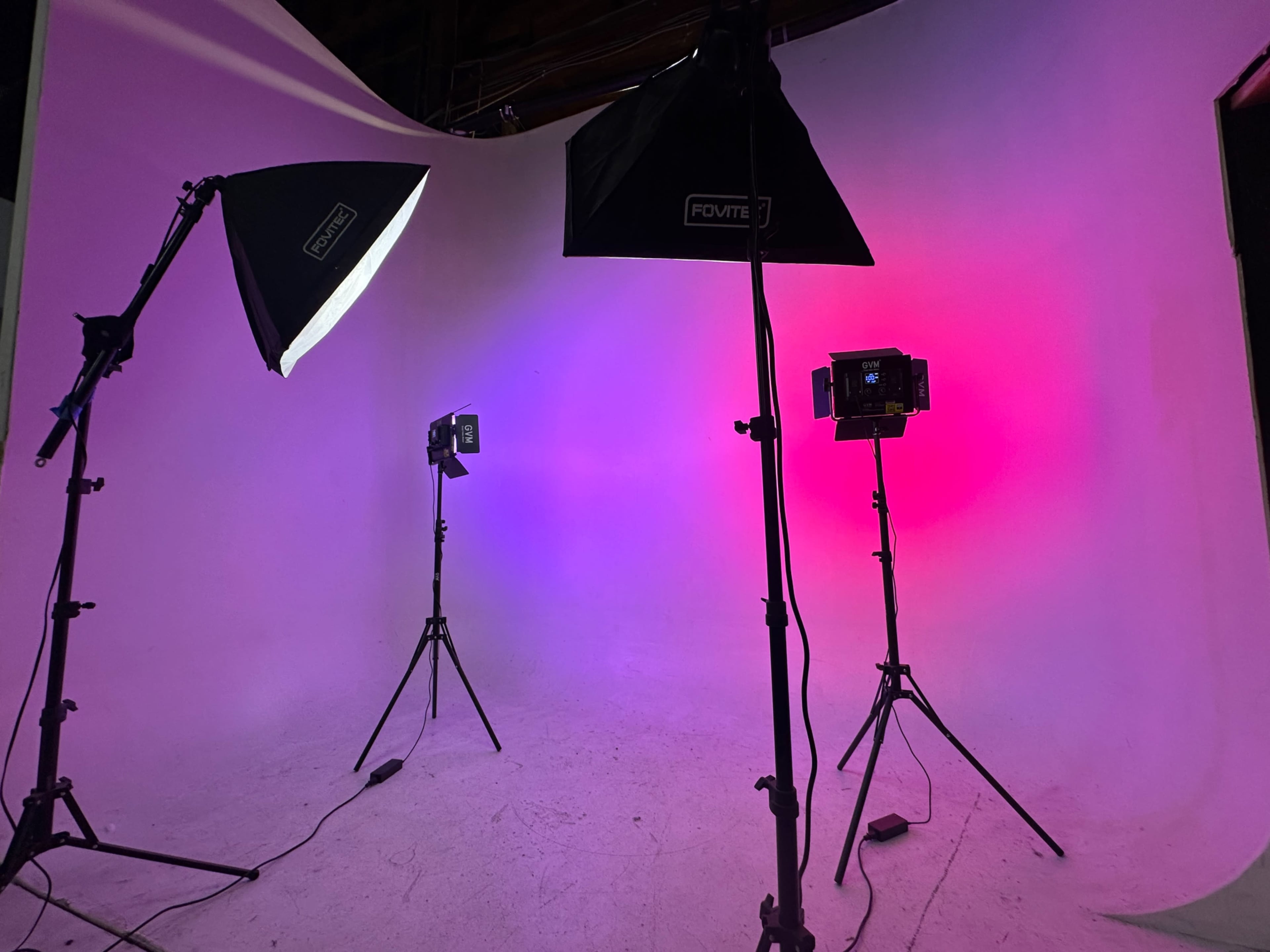 A photography studio with three lighting setups illuminating a backdrop in gradient colors.