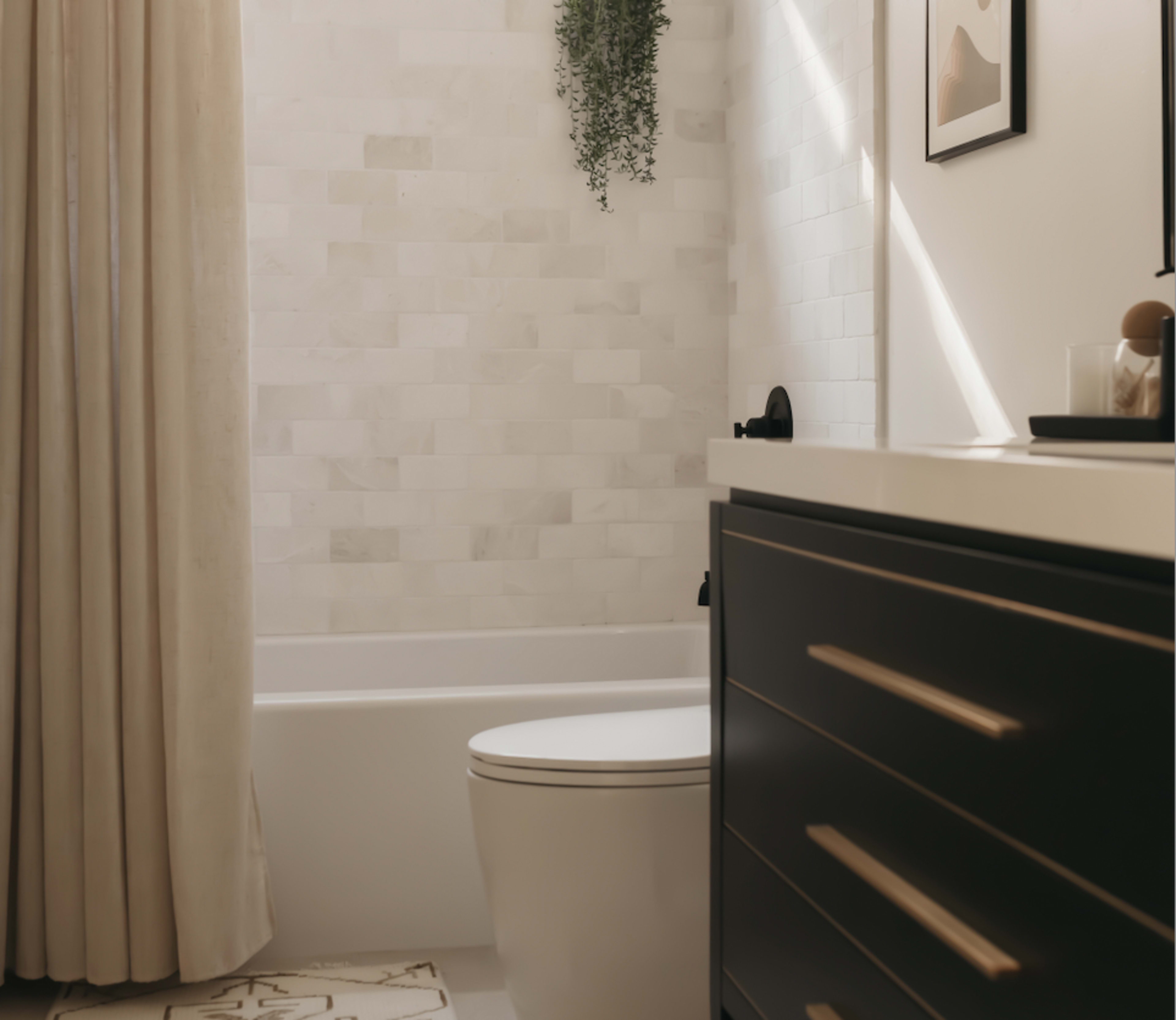 A modern bathroom featuring a white bathtub, a toilet, and a sink with dark cabinetry, complemented by a curtain and a small plant on the wall.