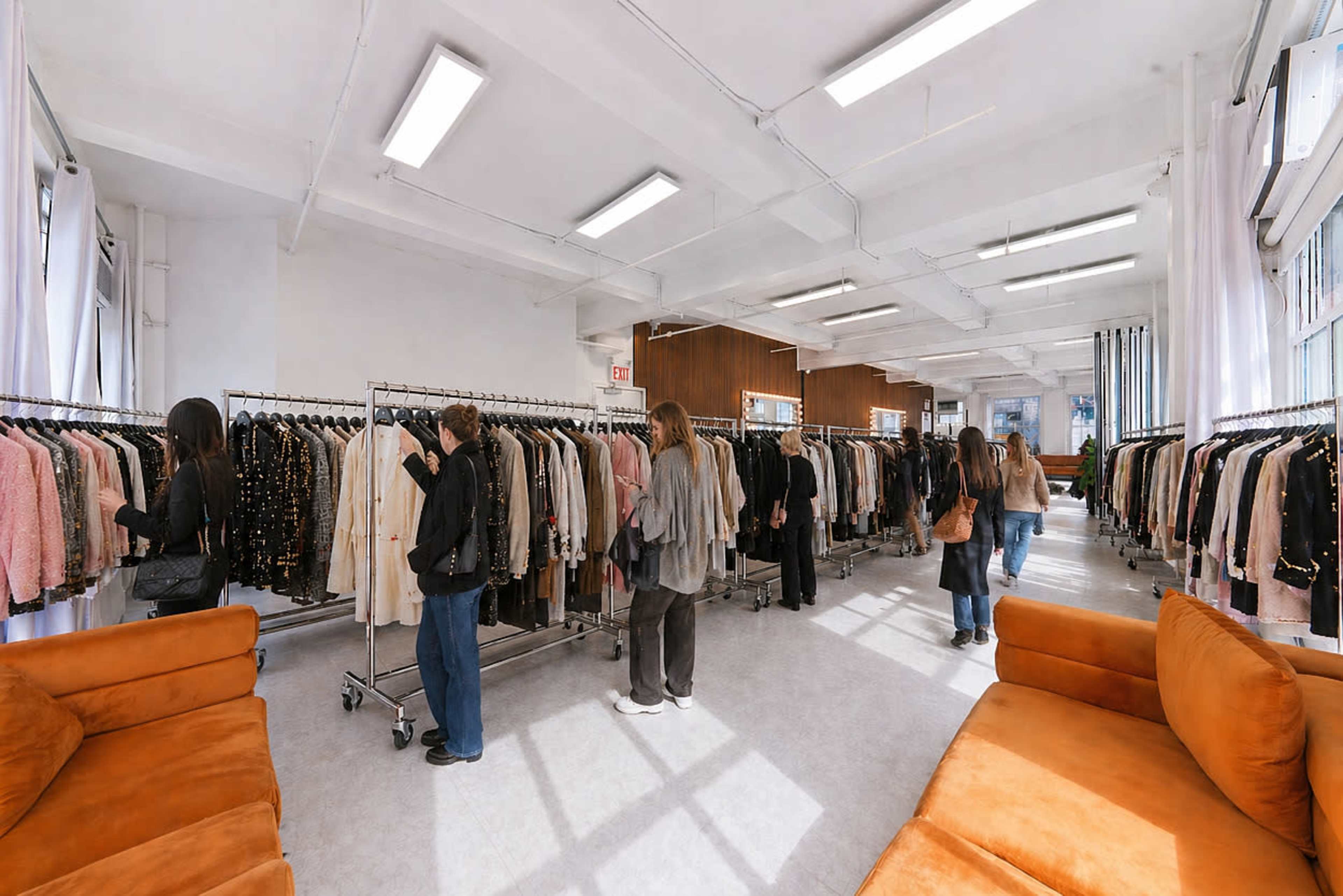 The scene features a spacious clothing boutique with racks of garments and several people browsing among them.