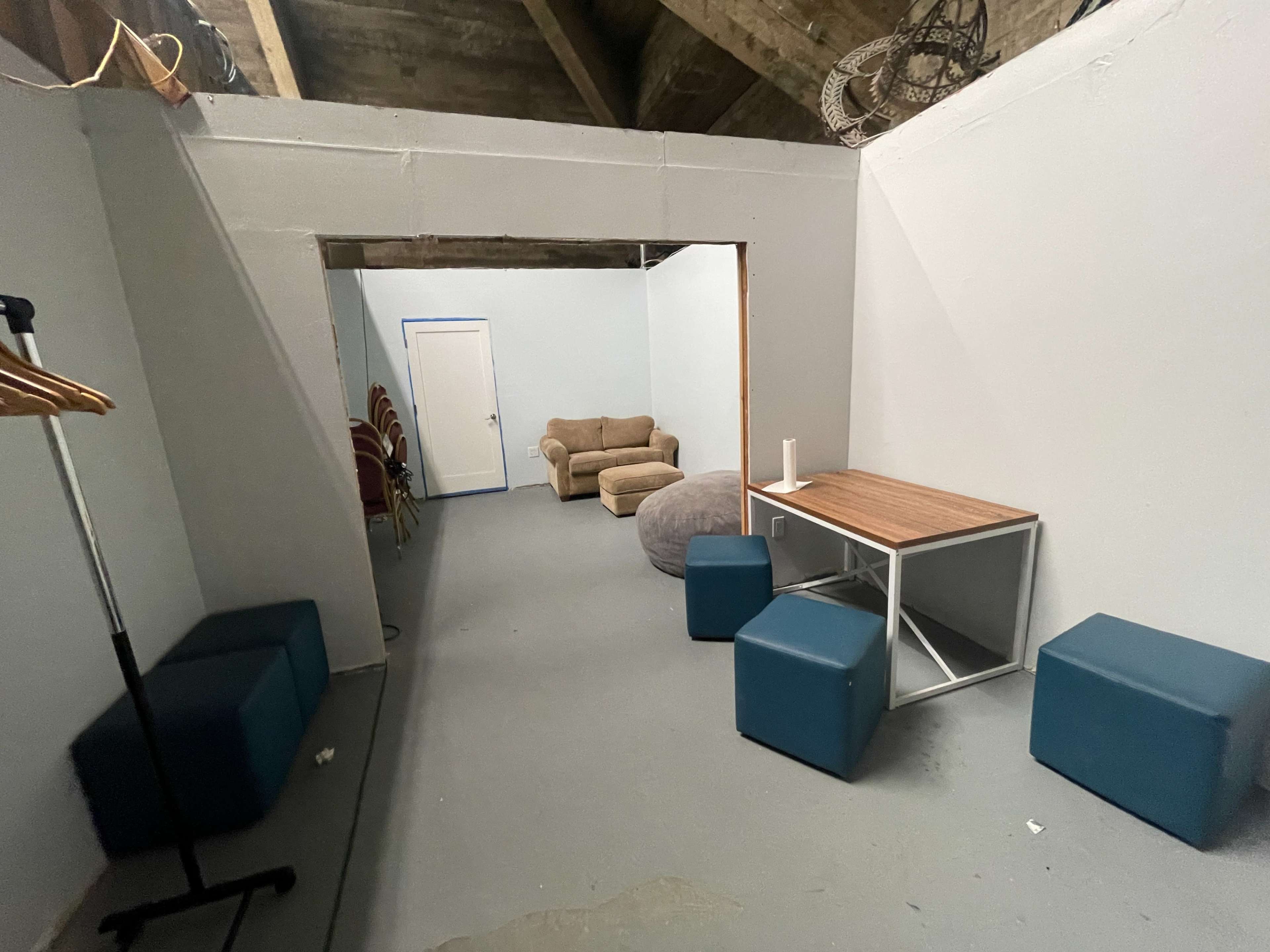 A simple interior space with a couch, bean bag, table, and several chairs along the wall.