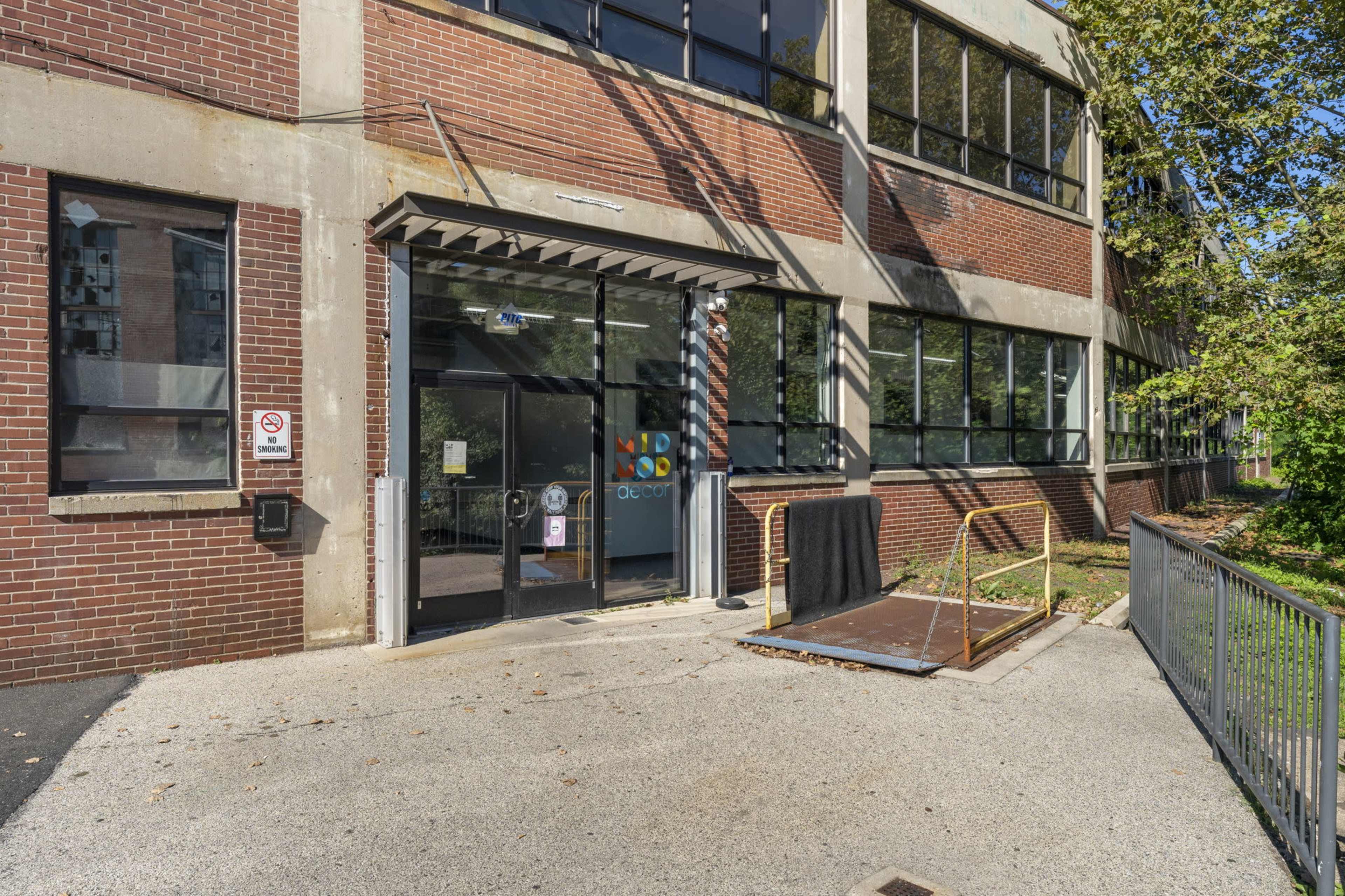 The entrance of a building featuring a ramp, large windows, and a sign with the word "Open."