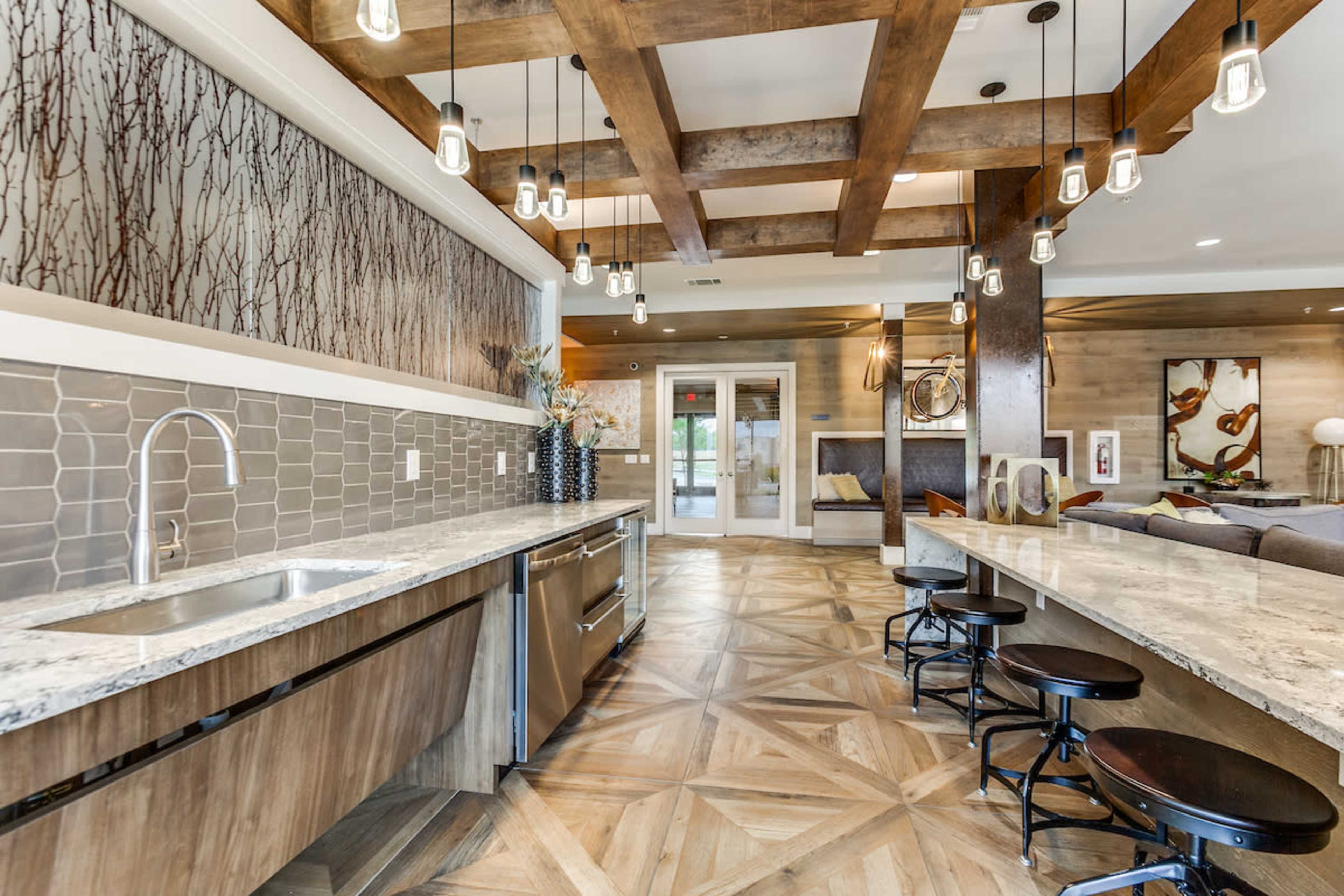 A spacious kitchen with a large island, wooden beams on the ceiling, and a combination of gray tile and countertop surfaces.