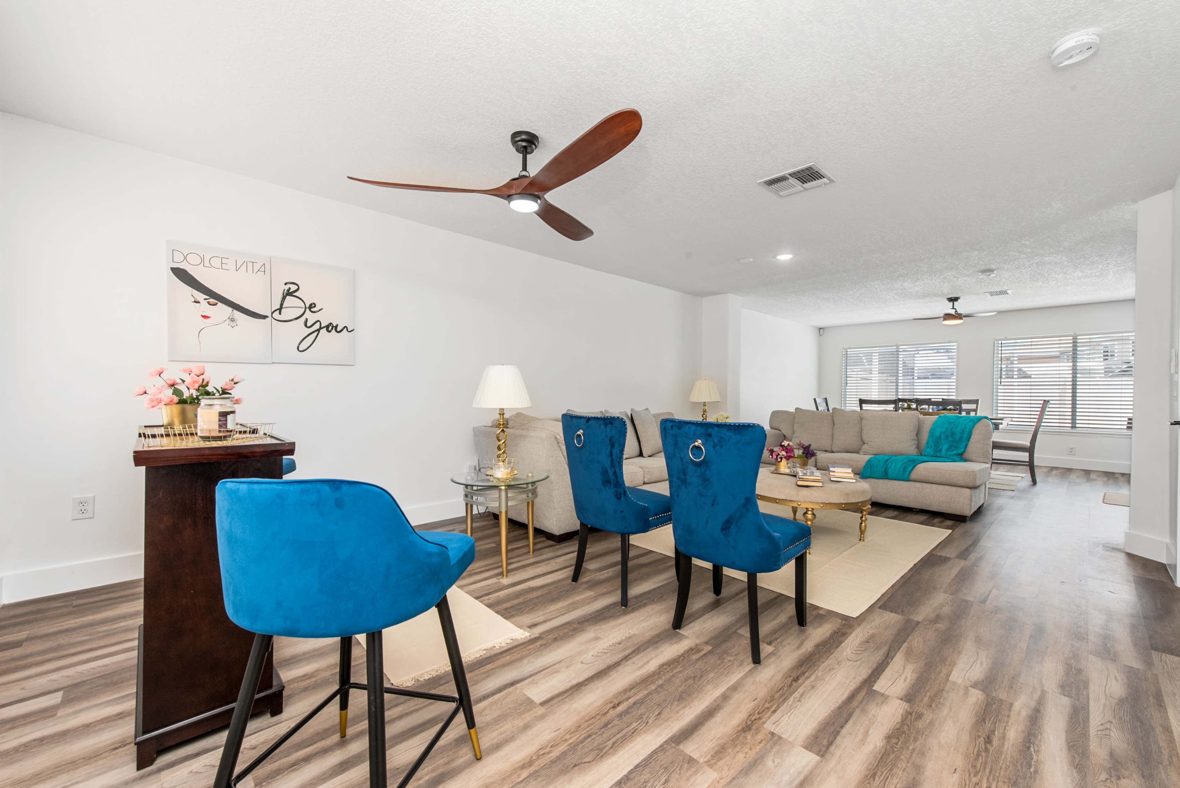 A contemporary living room with a seating area featuring a large couch, two blue chairs, and a decorative wall art piece.