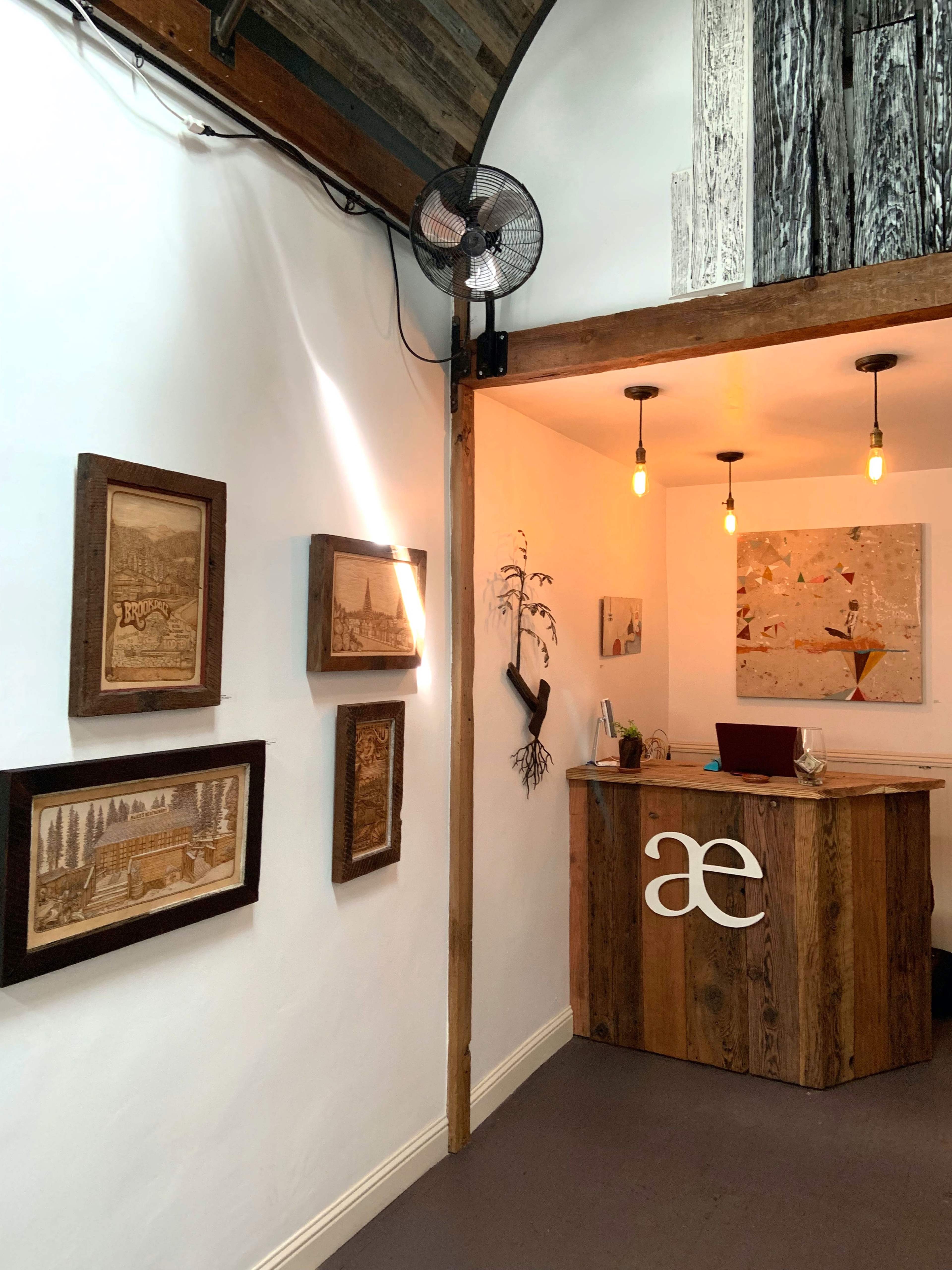 A boutique reception area featuring framed artwork on the walls and a wooden desk with a modern logo.