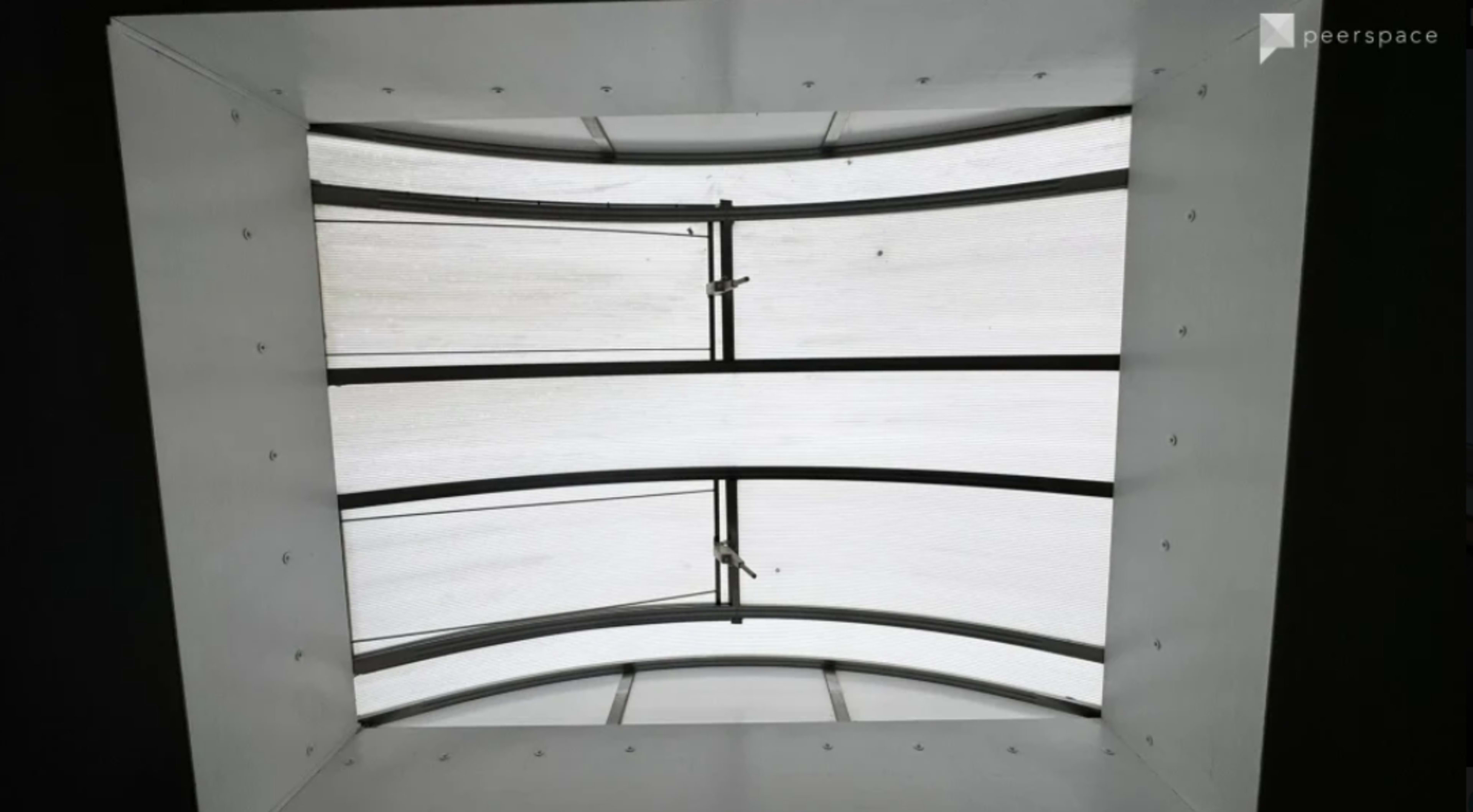 The image shows a view from below of a curved skylight with metal framing and translucent panels.