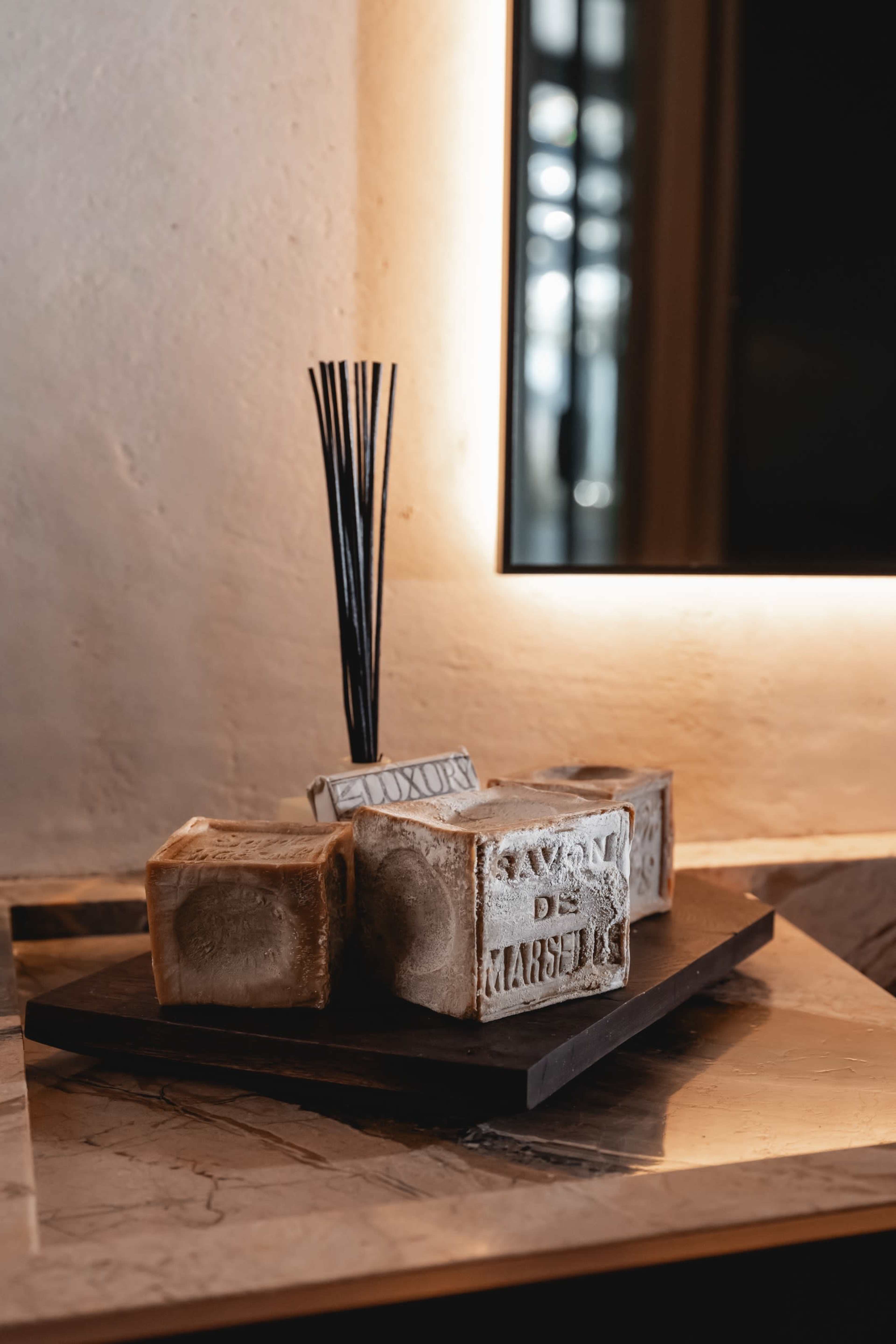 A wooden tray holds several decorative blocks and incense sticks in a softly lit setting.