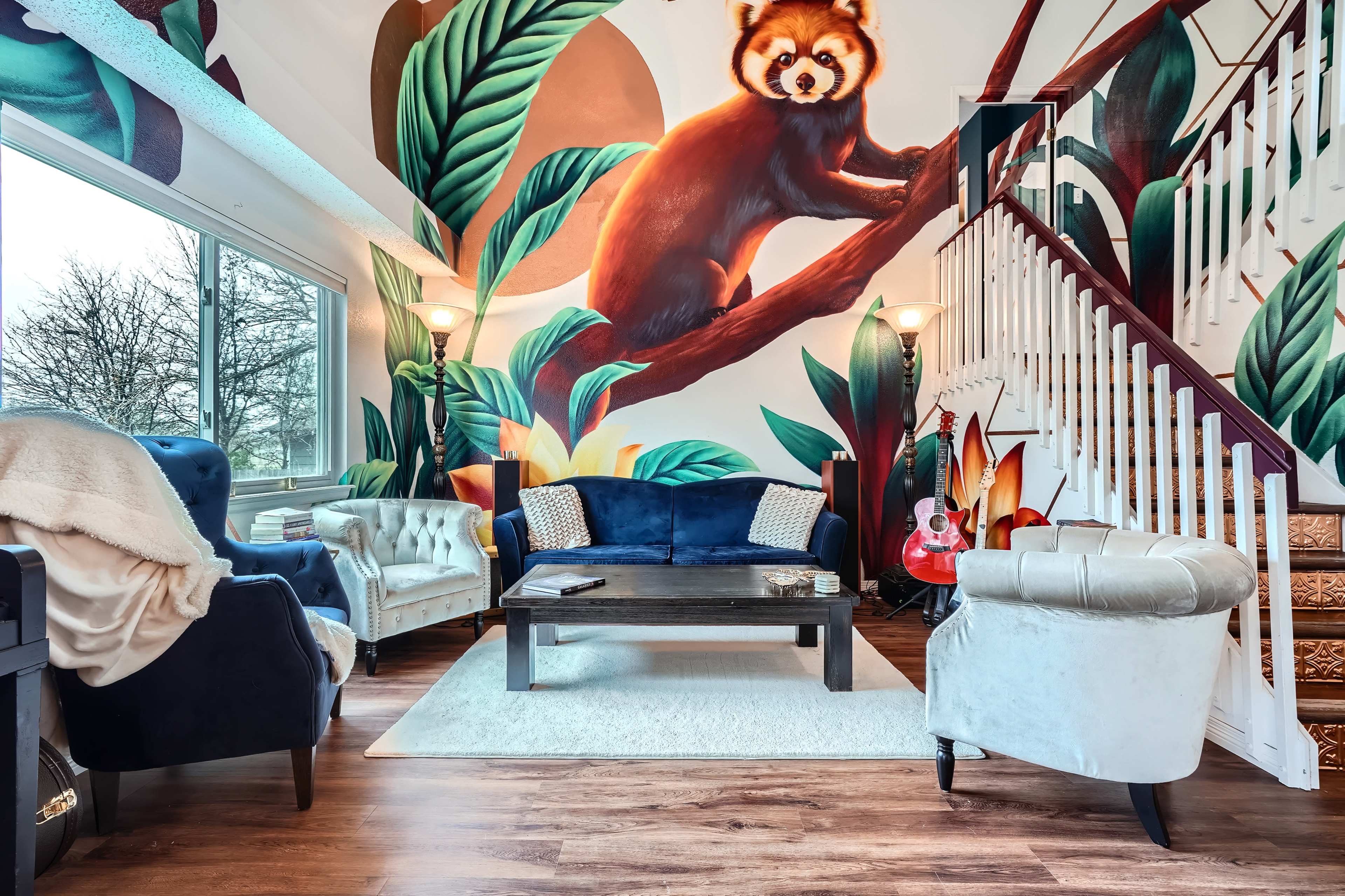 A cozy living room features a large wall mural of a bear amidst tropical leaves, with plush seating and a coffee table centered on a light rug.