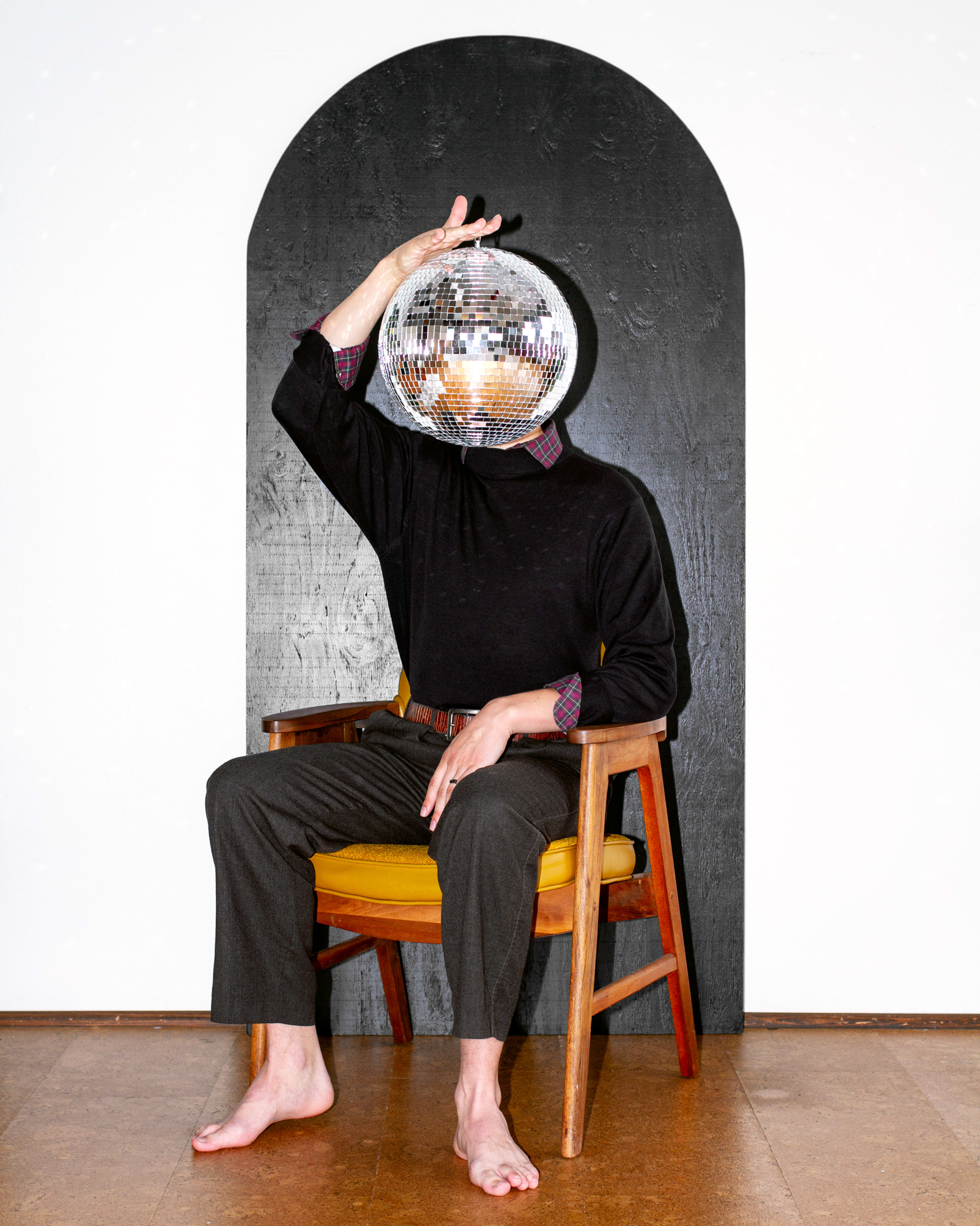 A fashion model posing for a photoshoot with a disco ball.