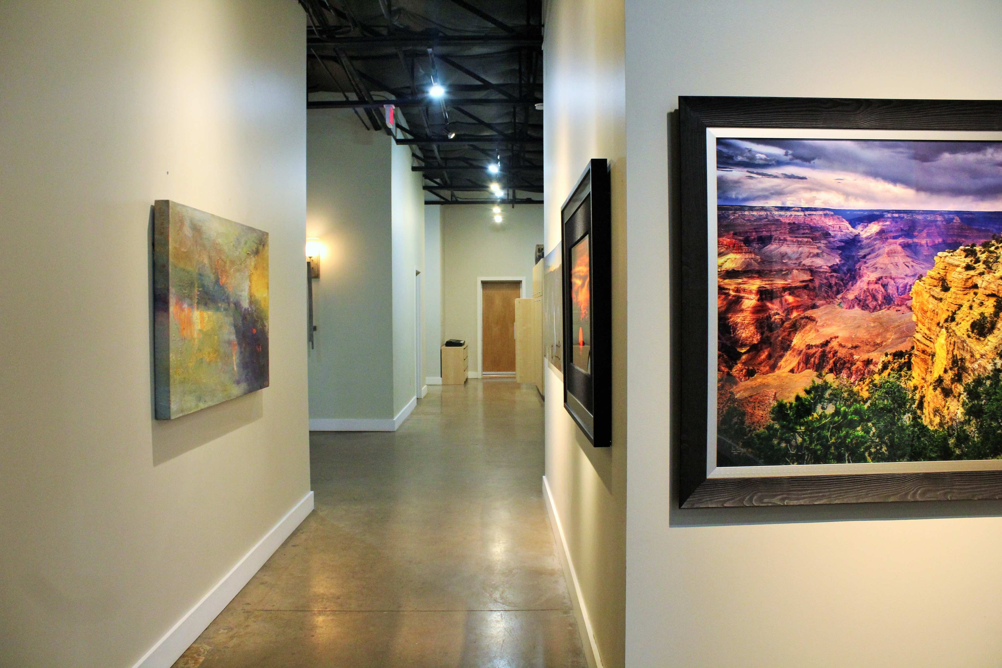 A long, narrow hallway is lined with artwork on the walls, leading to a door at the end.