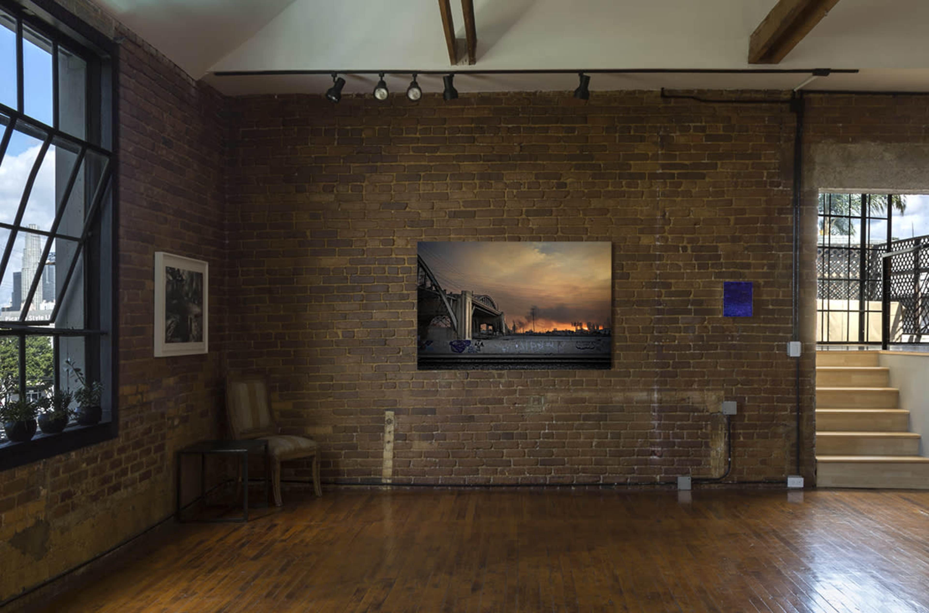 An interior of a modern, open-concept room with exposed brick walls, large windows, and a digital artwork displayed on the wall.