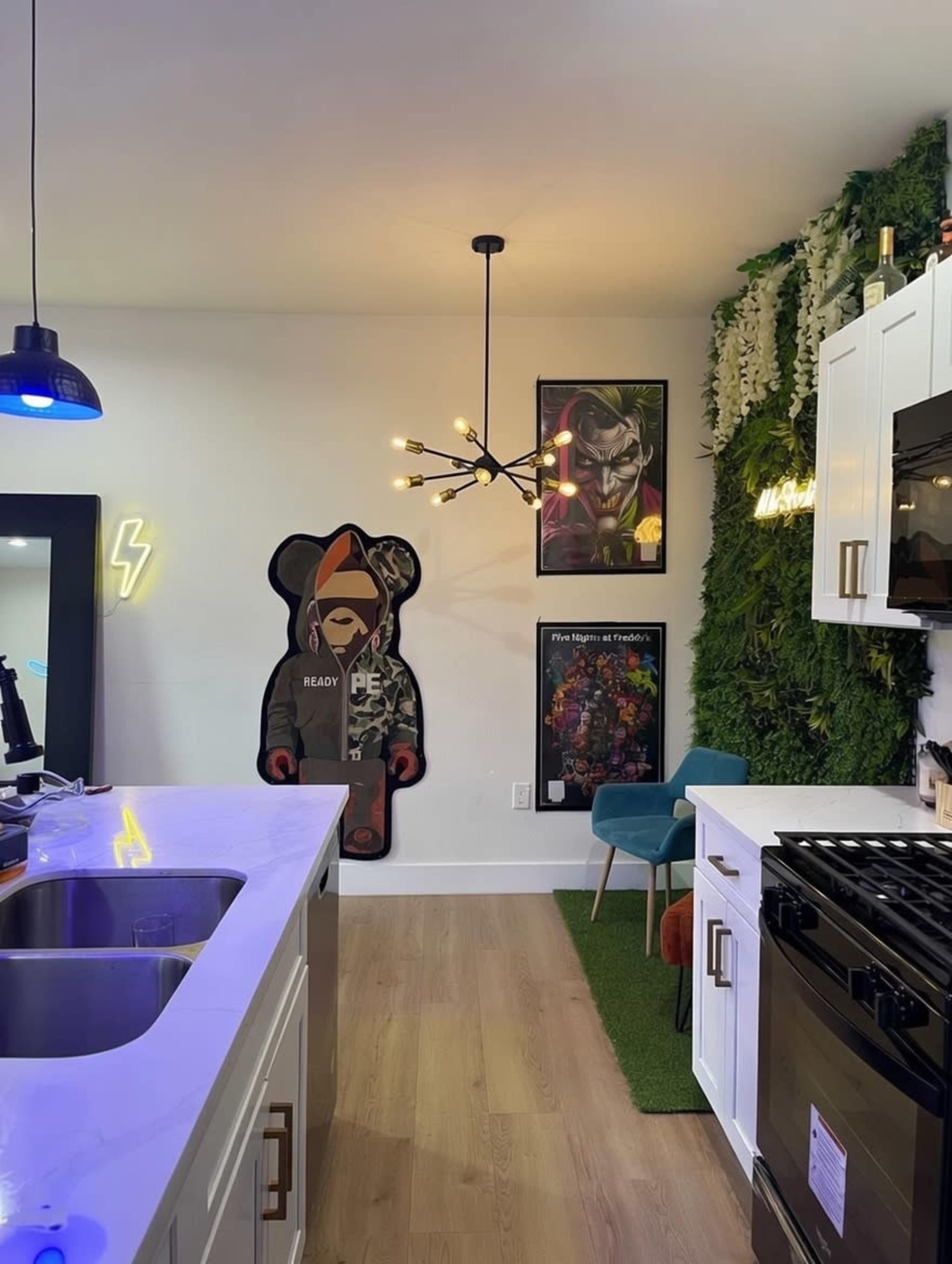 The image shows a modern kitchen with white cabinets, a black stove, a large bear-shaped wall decoration, and framed artwork on the walls.
