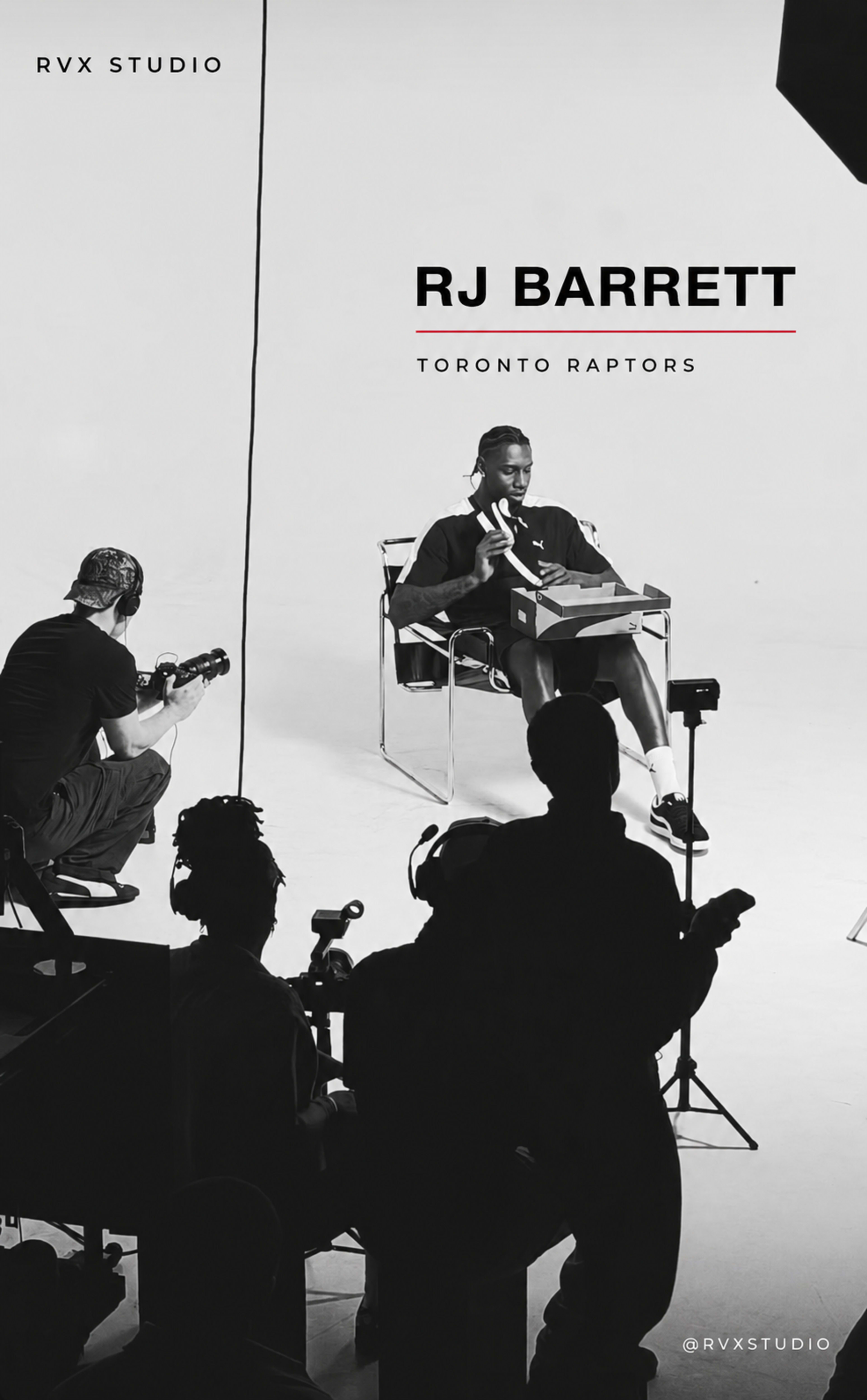 The image shows a photoshoot with a man seated in a chair, holding a basketball, while several crew members operate cameras and lighting equipment in a studio setting.