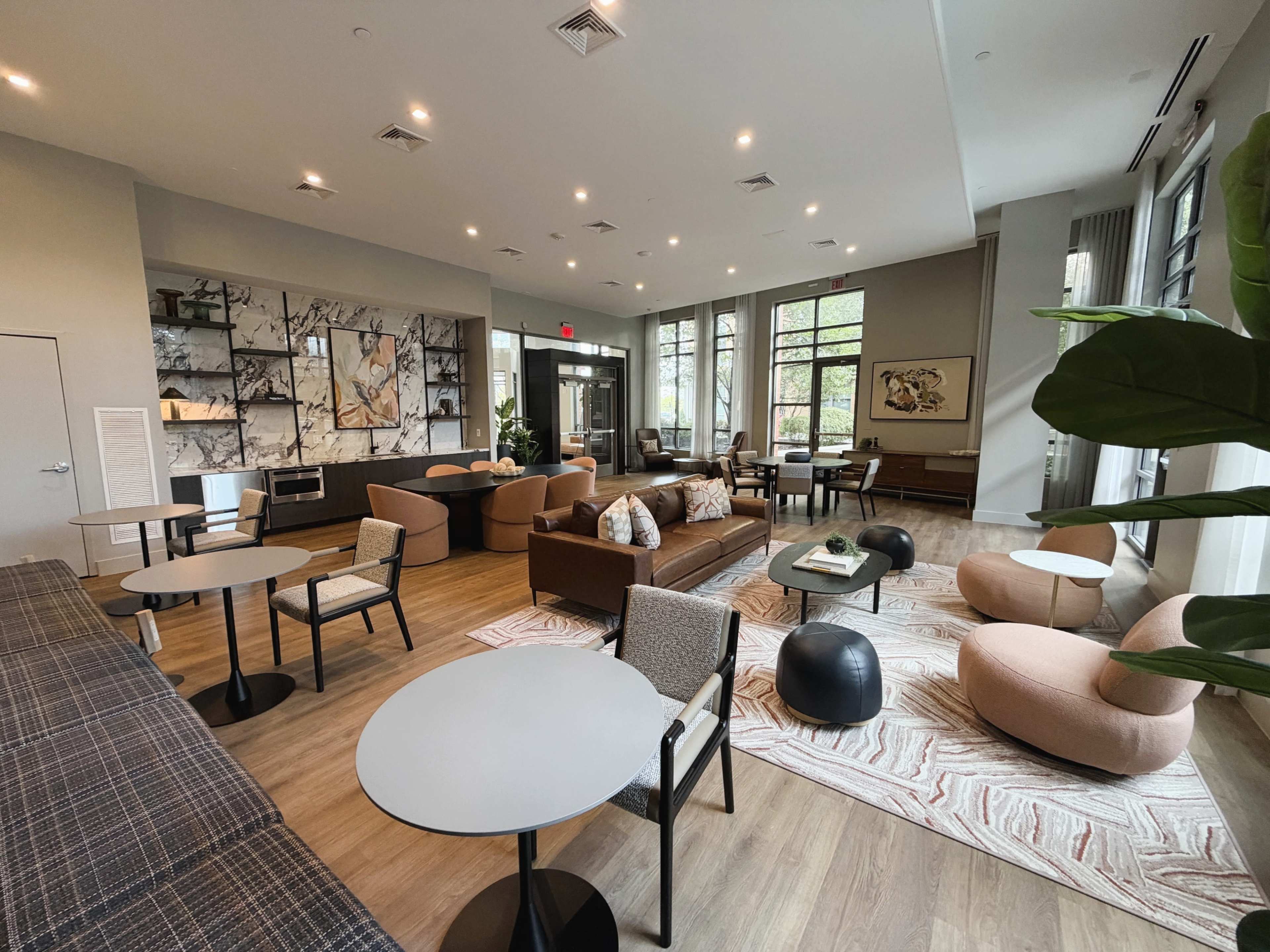The image shows a spacious lounge area with modern seating, large windows, and decorative artwork on the walls.