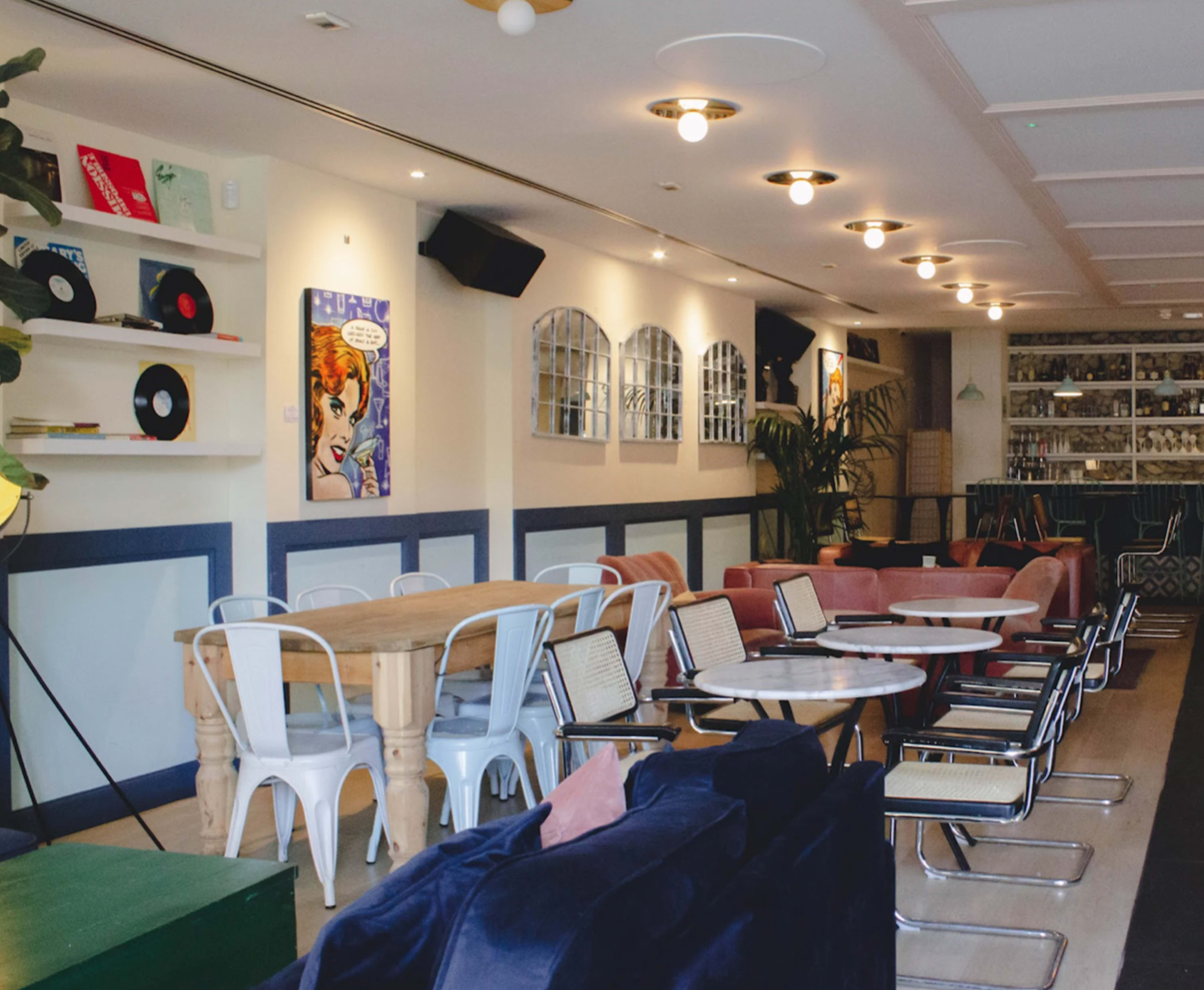 A cozy café interior with a mix of seating options, colorful artwork on the walls, and vinyl records displayed on shelves.