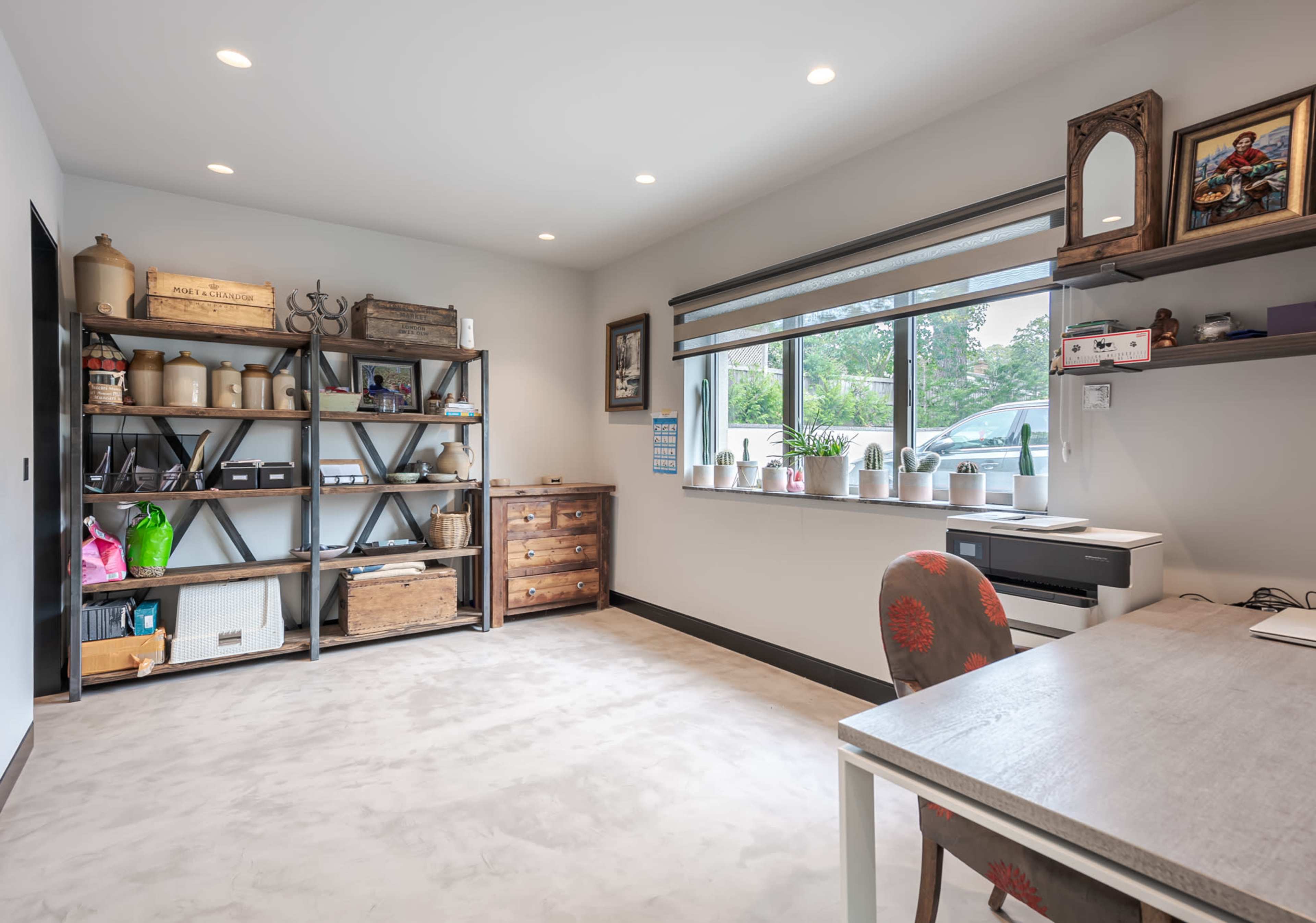 A well-lit room features a wooden desk and shelving unit filled with various storage boxes and decorative items.