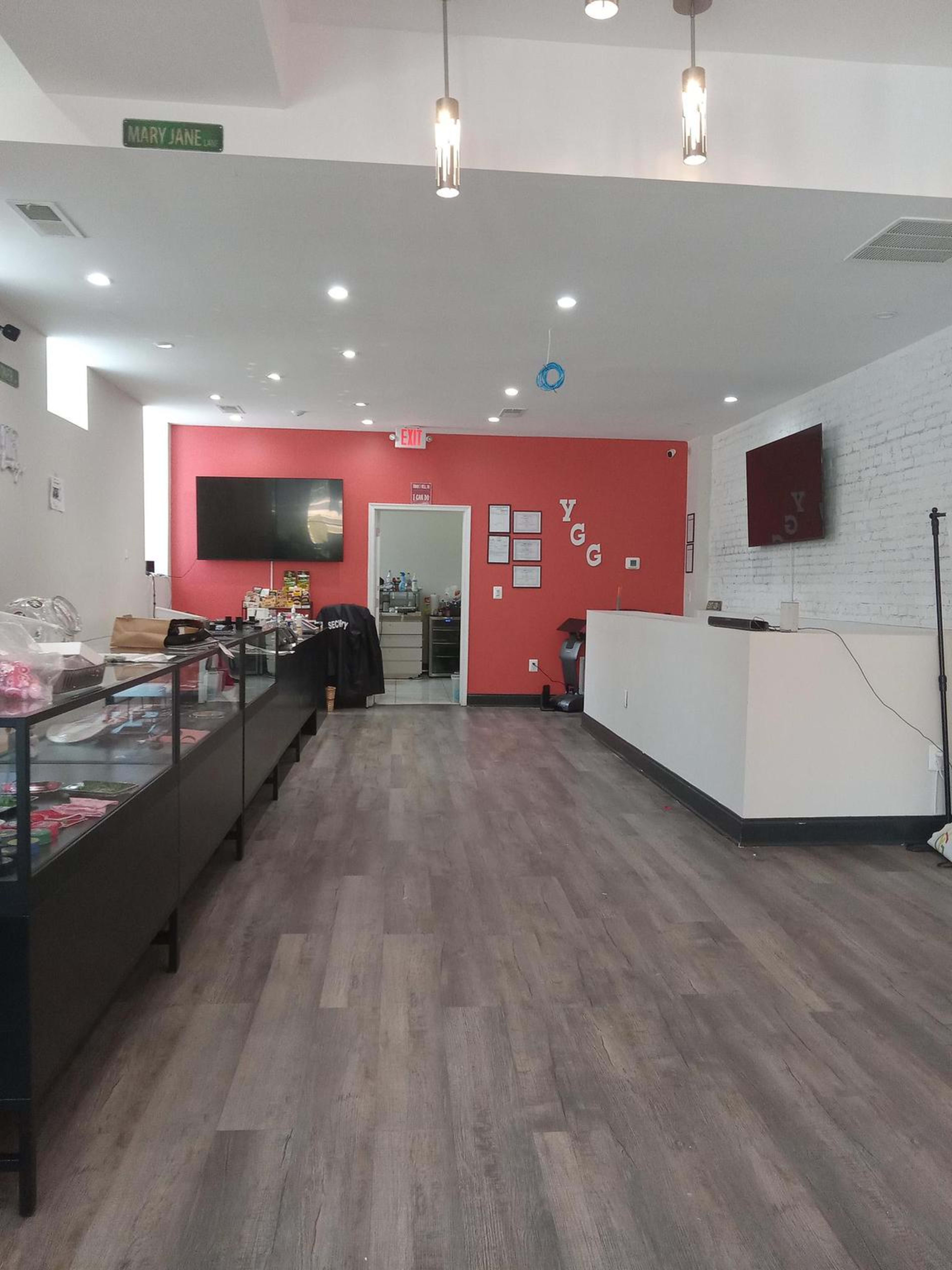 The image shows the interior of a retail space with a red accent wall, display counters on the left, and a reception area on the right.