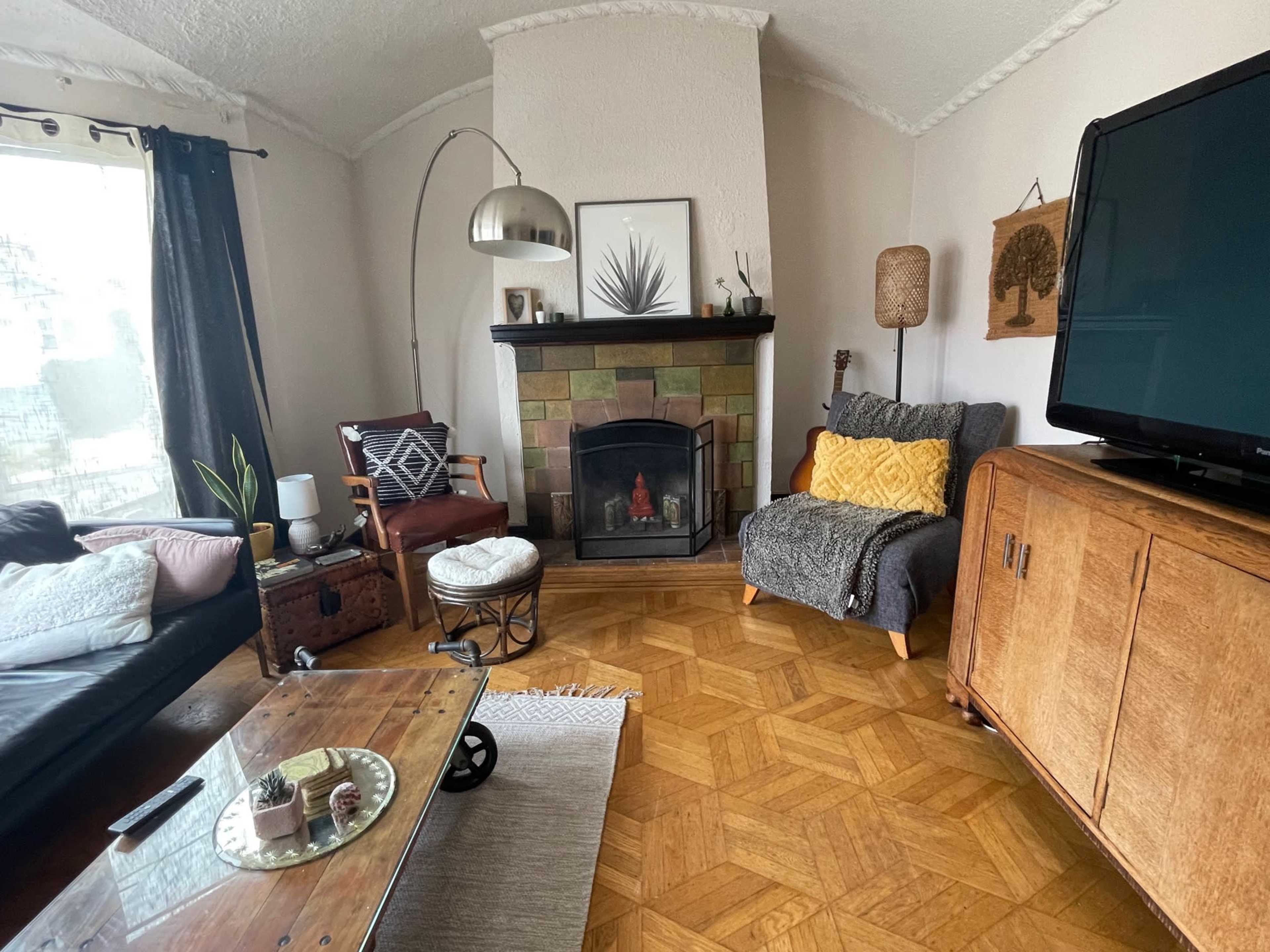 A cozy living room featuring a fireplace, a wooden coffee table, a television, and a mix of comfortable seating arrangements.