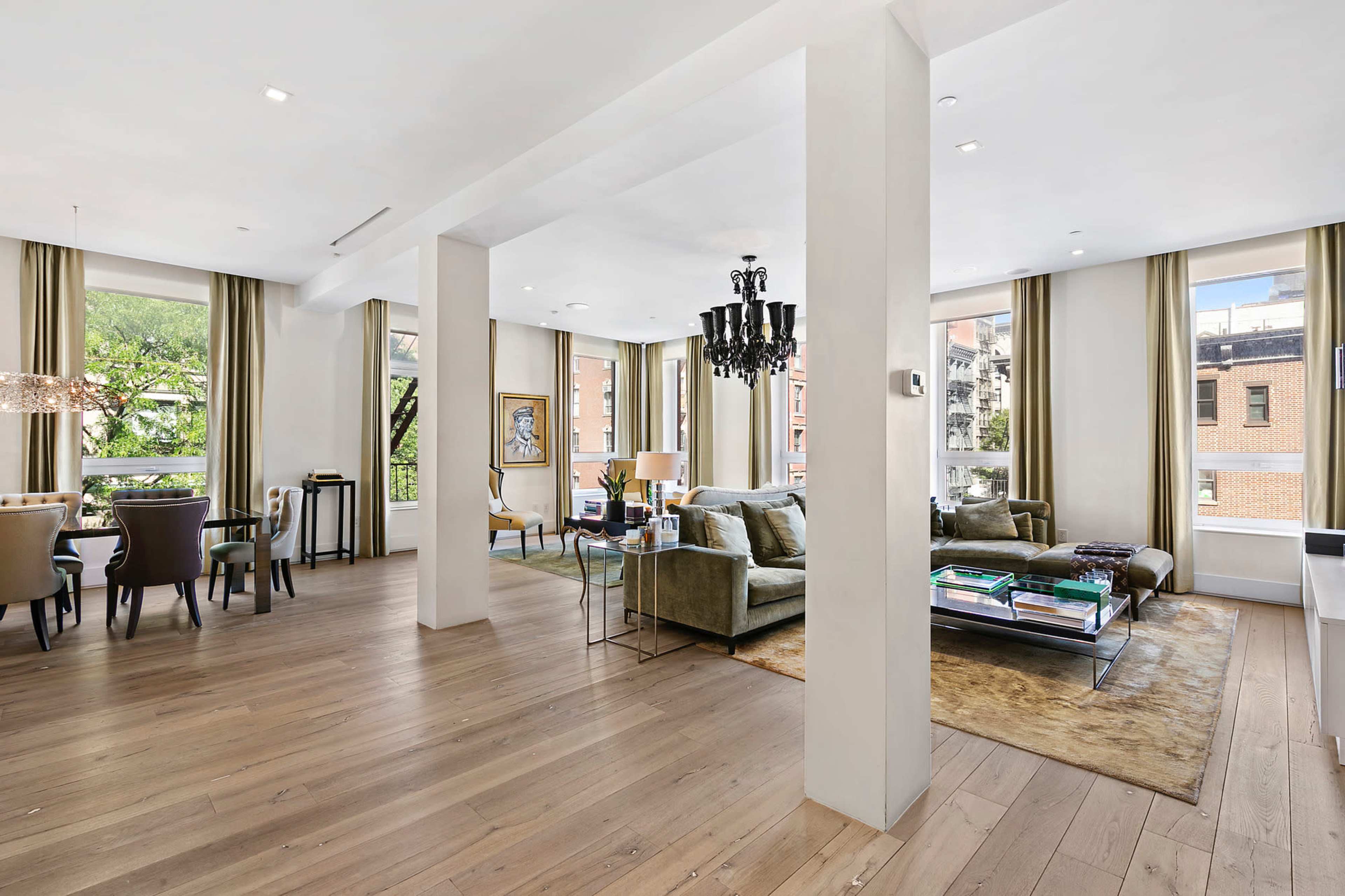 A spacious, bright living area featuring a seating arrangement, dining area, and large windows that allow natural light to fill the room.