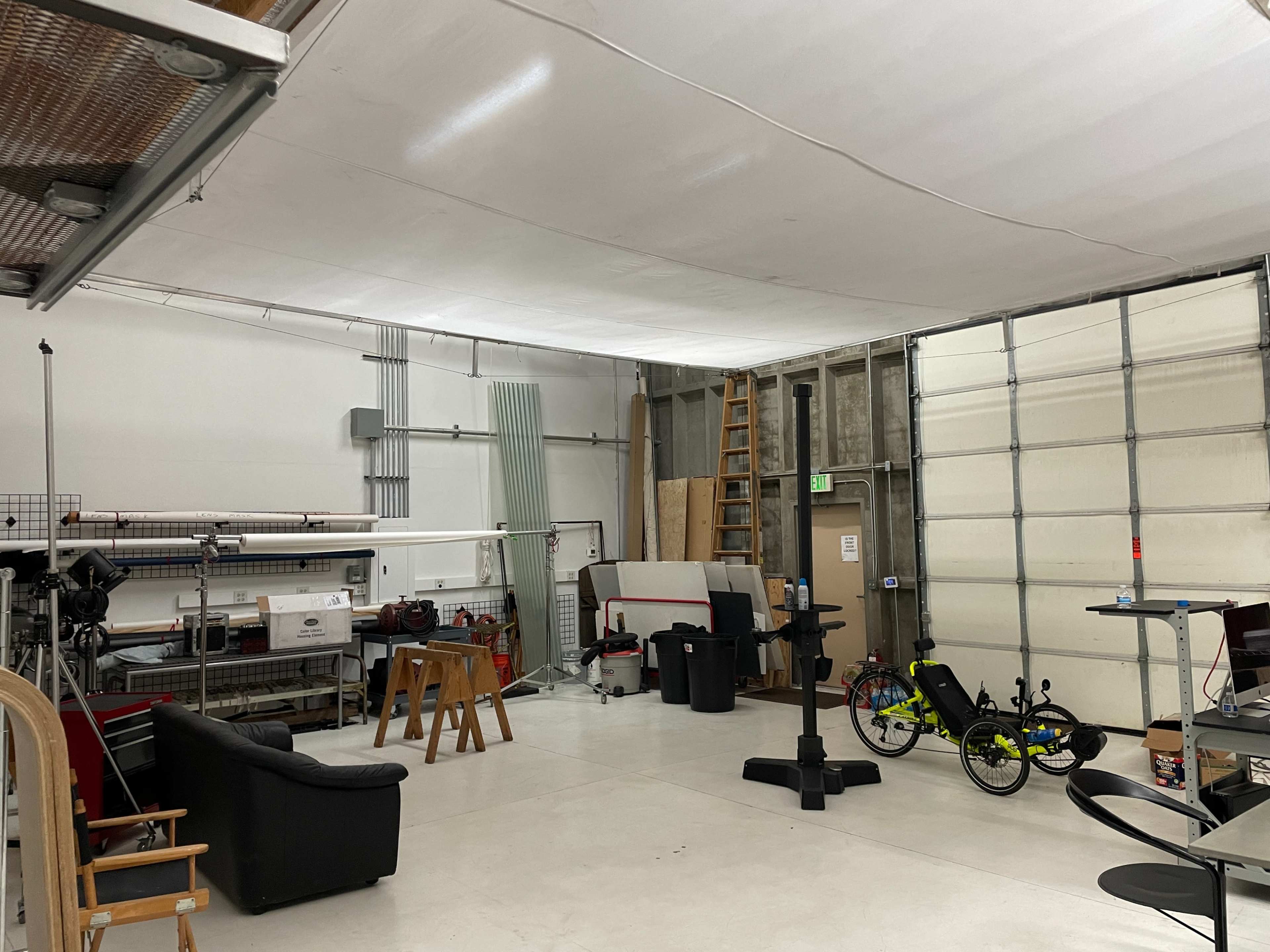 A spacious garage or workshop with various equipment, furniture, and bicycles arranged inside.