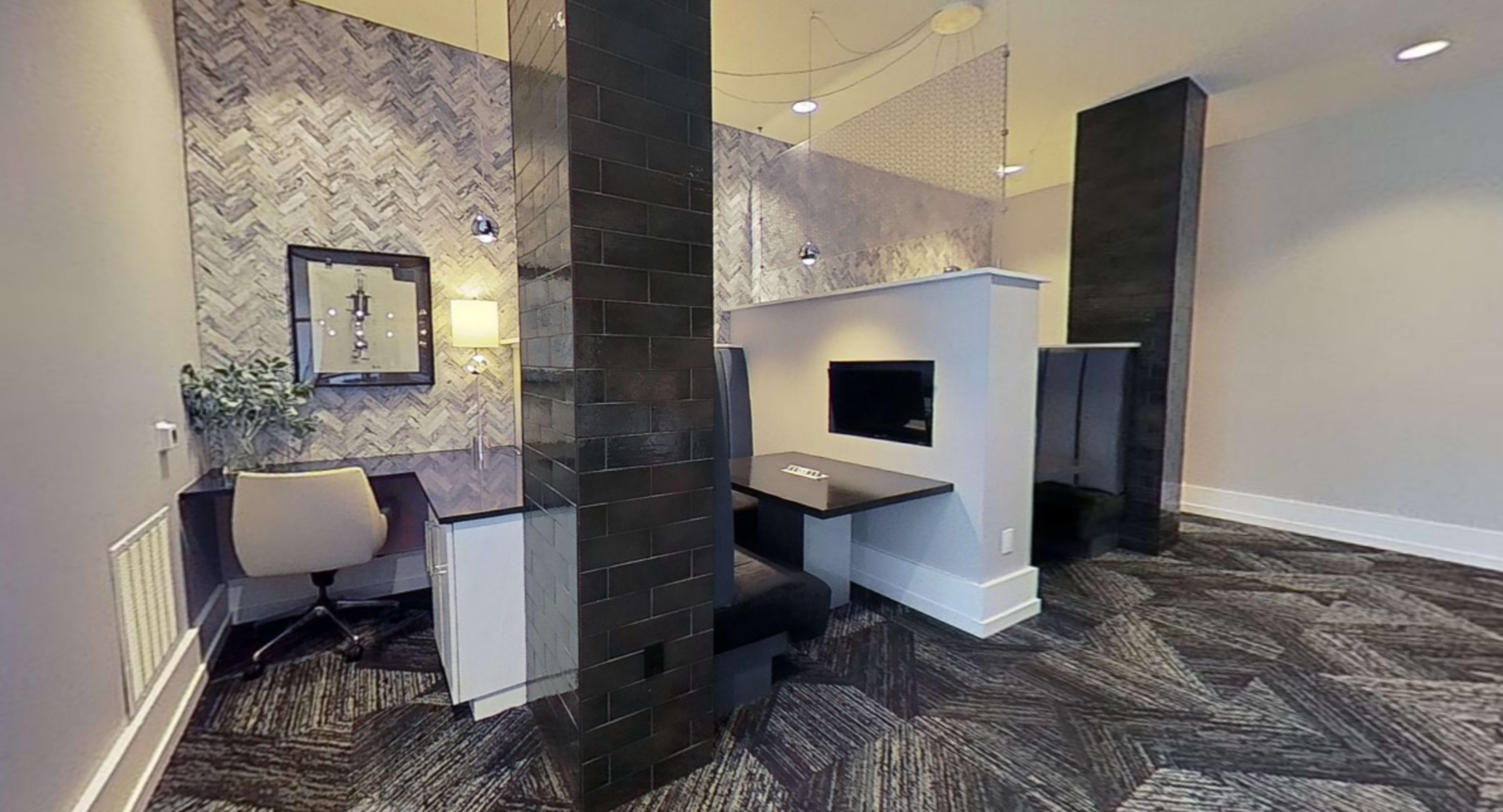 A modern office space featuring a desk area with a chair, a wall-mounted television, and decorative partitions creating separate zones.