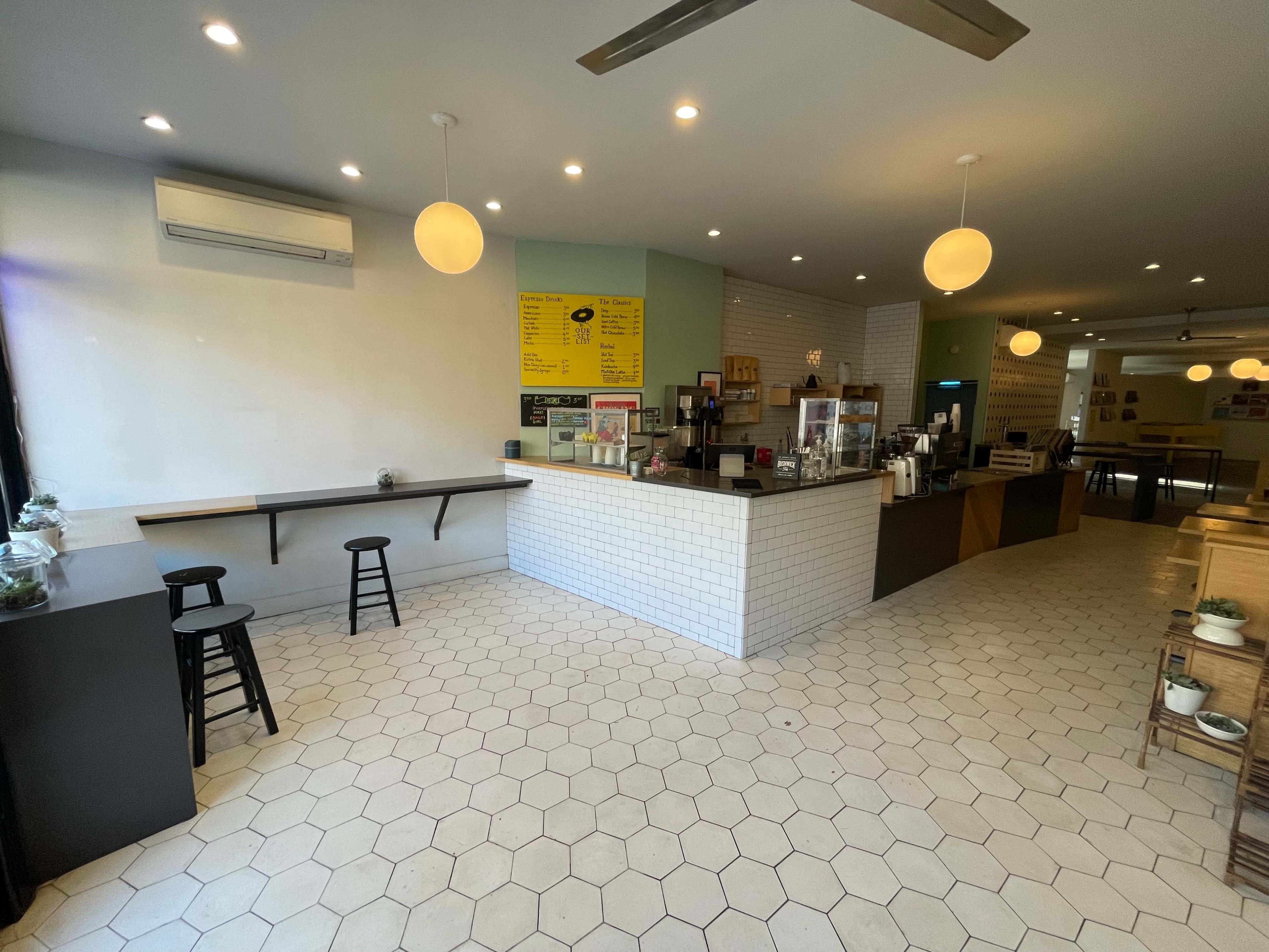 A modern café interior with a payment counter, seating area, and hexagonal tiled flooring.