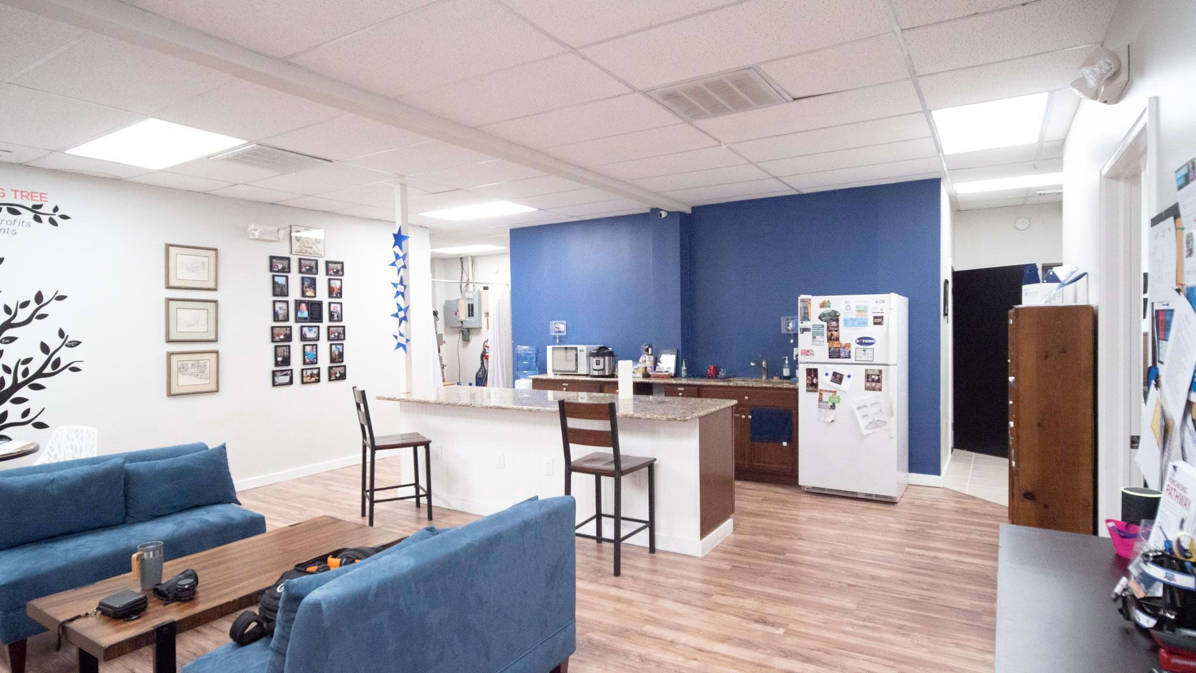 A spacious, modern common area featuring a kitchen with a bar, seating arrangements, and wall decorations.