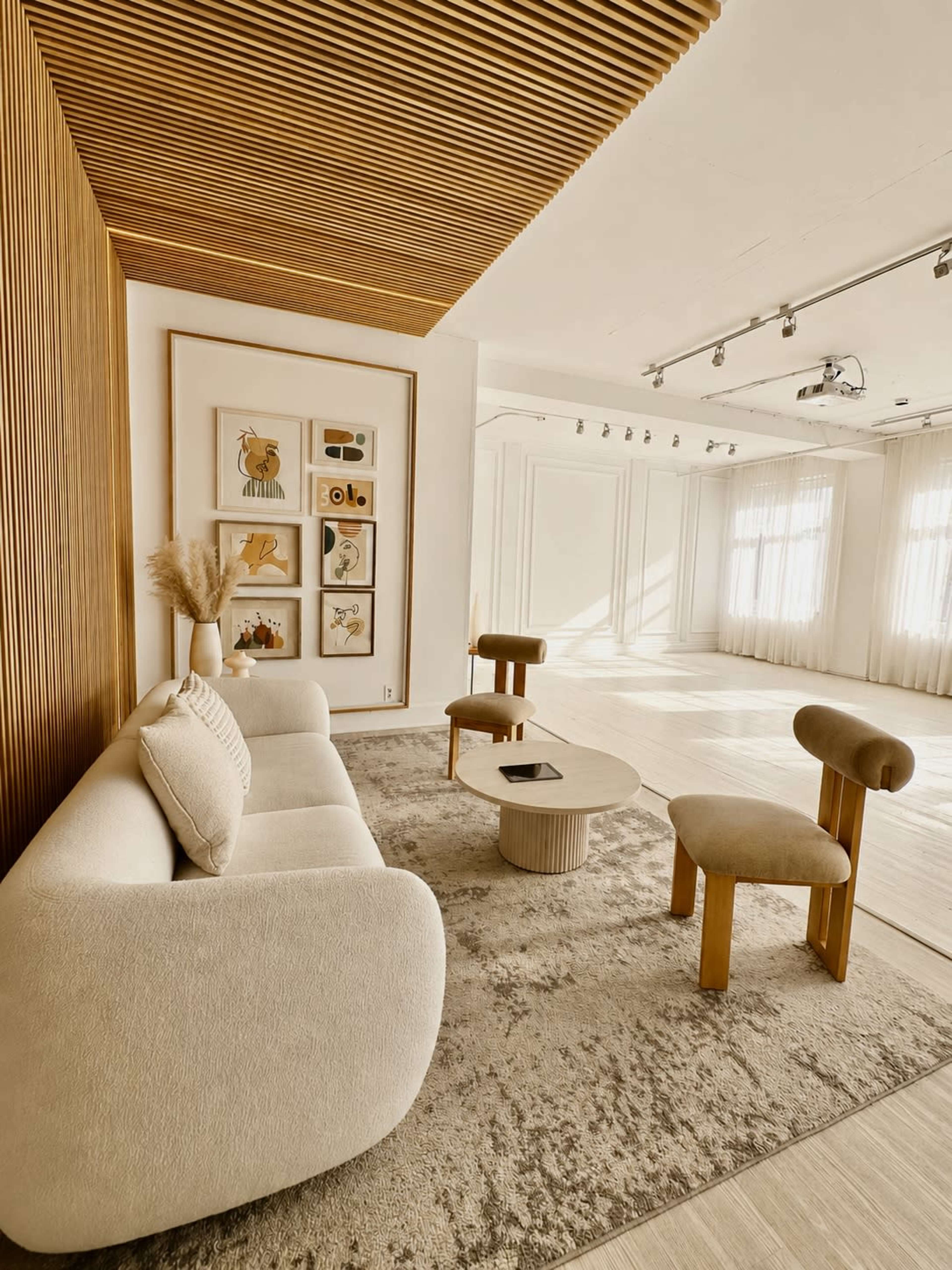 The image shows a modern interior space featuring a cozy seating area with a light-colored sofa, a round coffee table, and artistic wall decor.