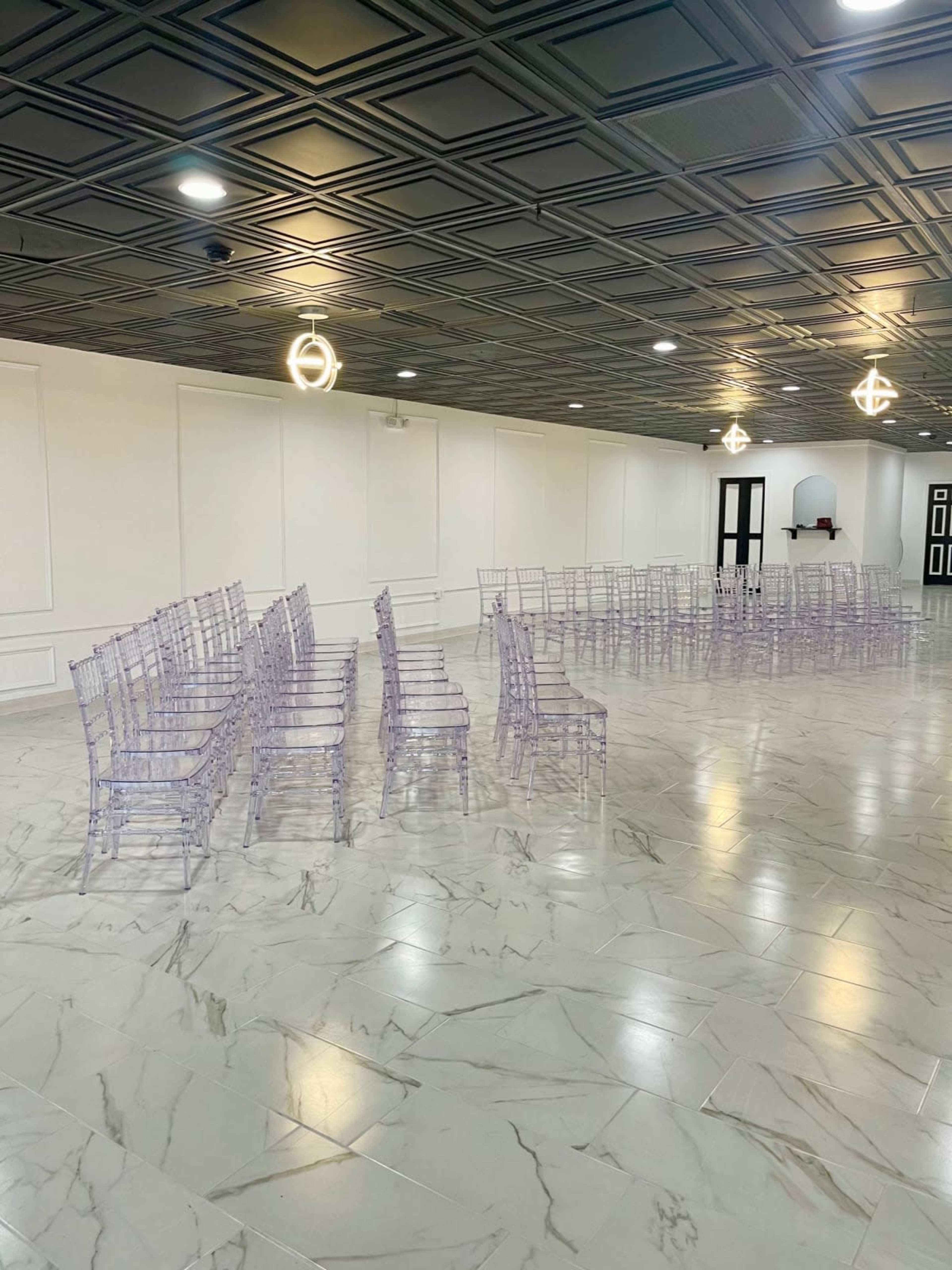 A white room with a marble floor featuring rows of transparent chairs arranged in a semi-circle.