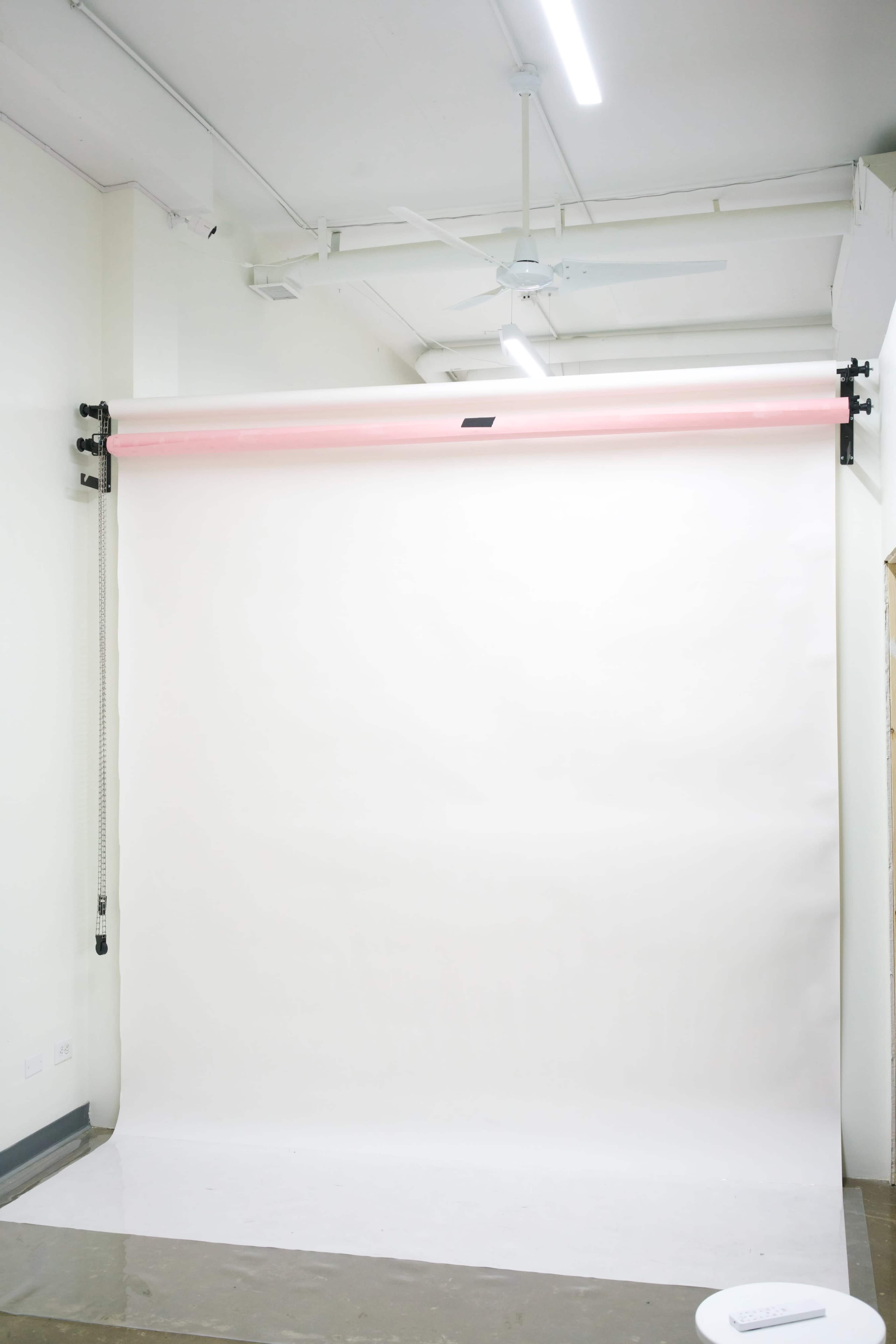 A blank white backdrop is mounted on a wall in a well-lit studio.