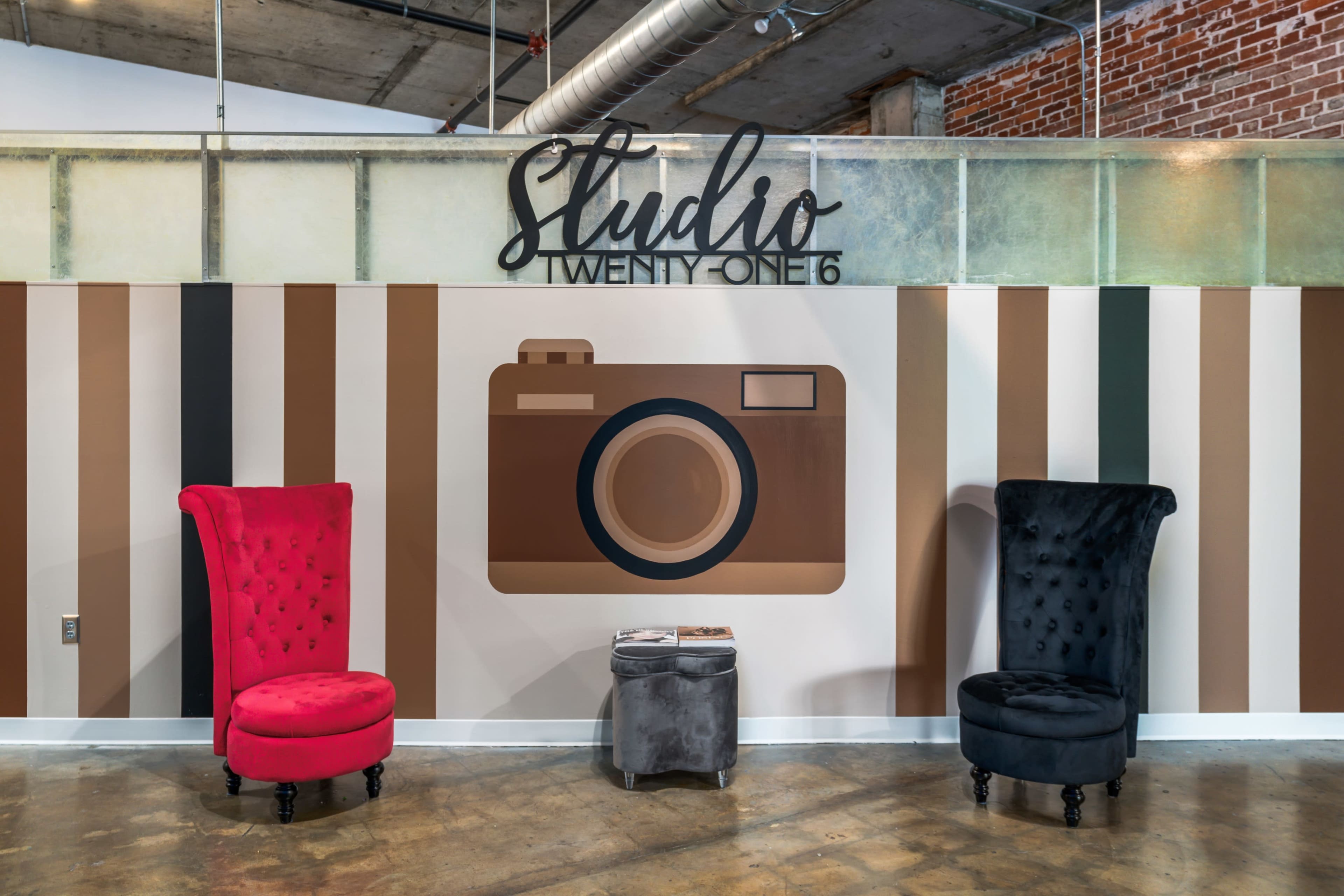 A stylish interior with a camera mural on the wall, featuring two distinct chairs in red and black, accompanied by a small table.
