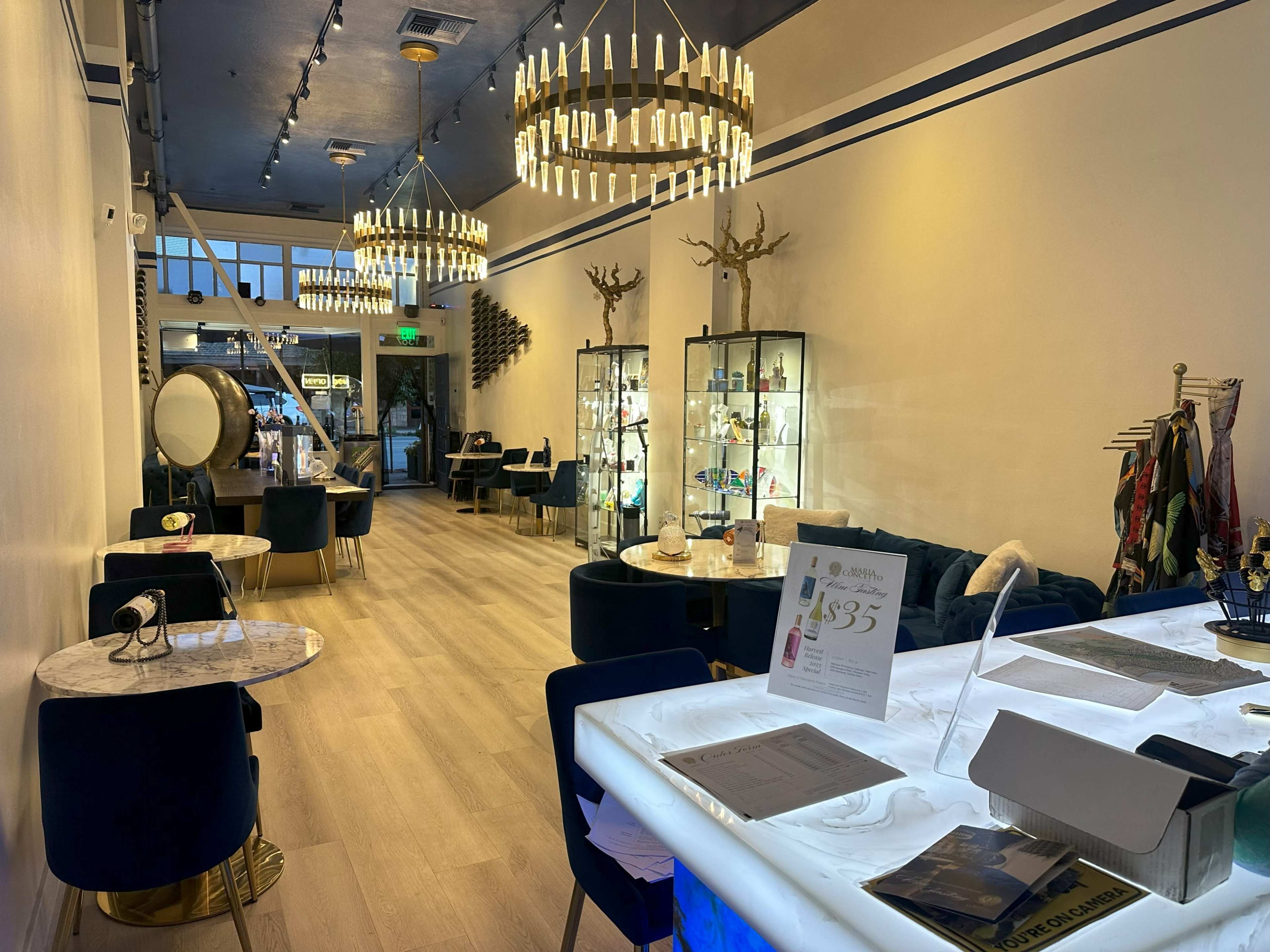 A modern interior of a boutique with elegant lighting, display cases filled with merchandise, and stylish seating arrangements along the sides.