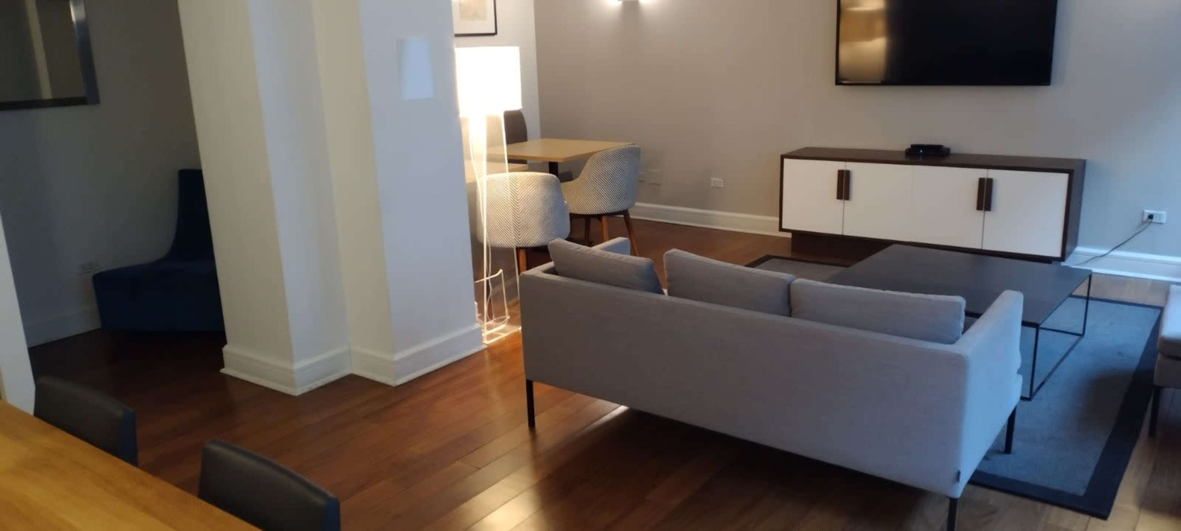A modern living room and dining area featuring a gray sofa, a coffee table, and a dining table with chairs.