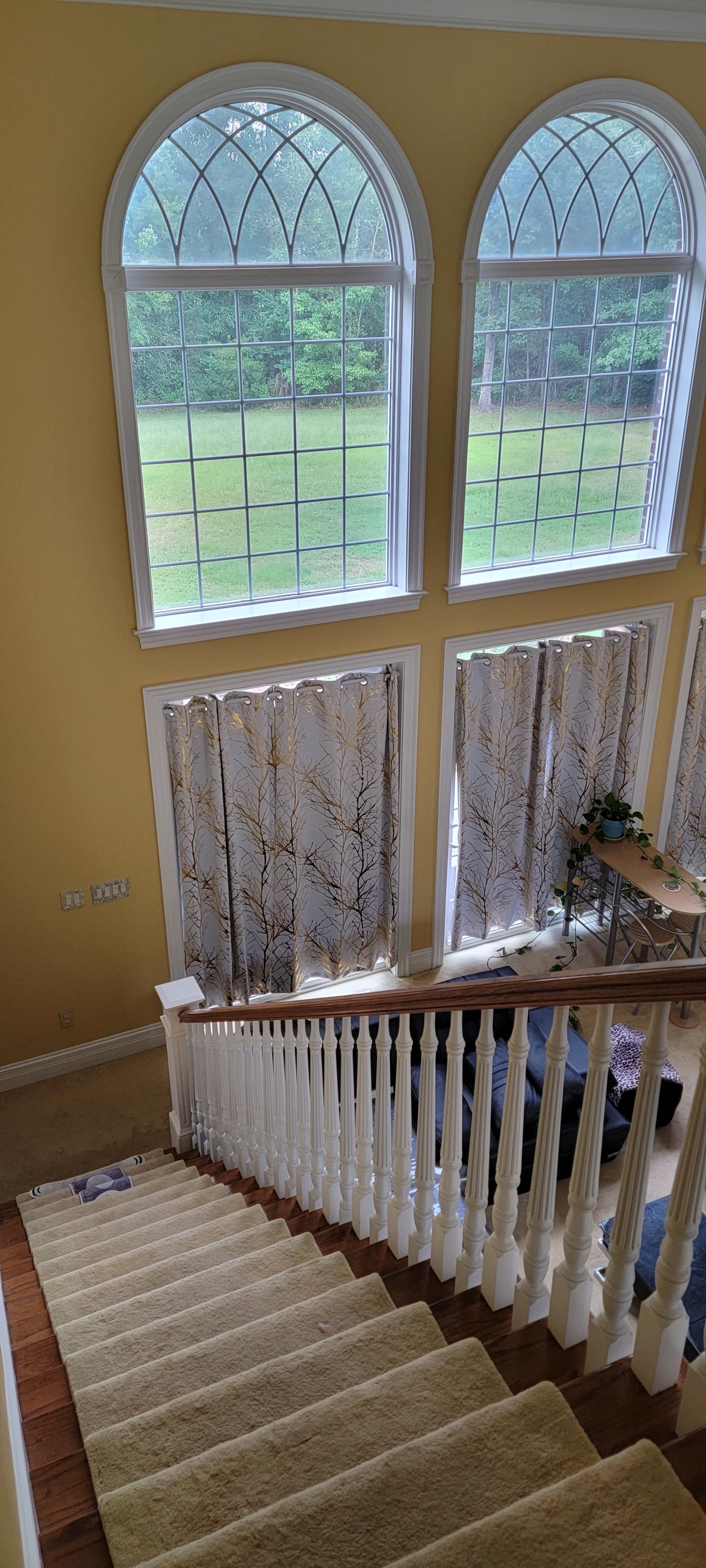 A staircase leading down to a living space, with large arched windows allowing natural light to illuminate the area.