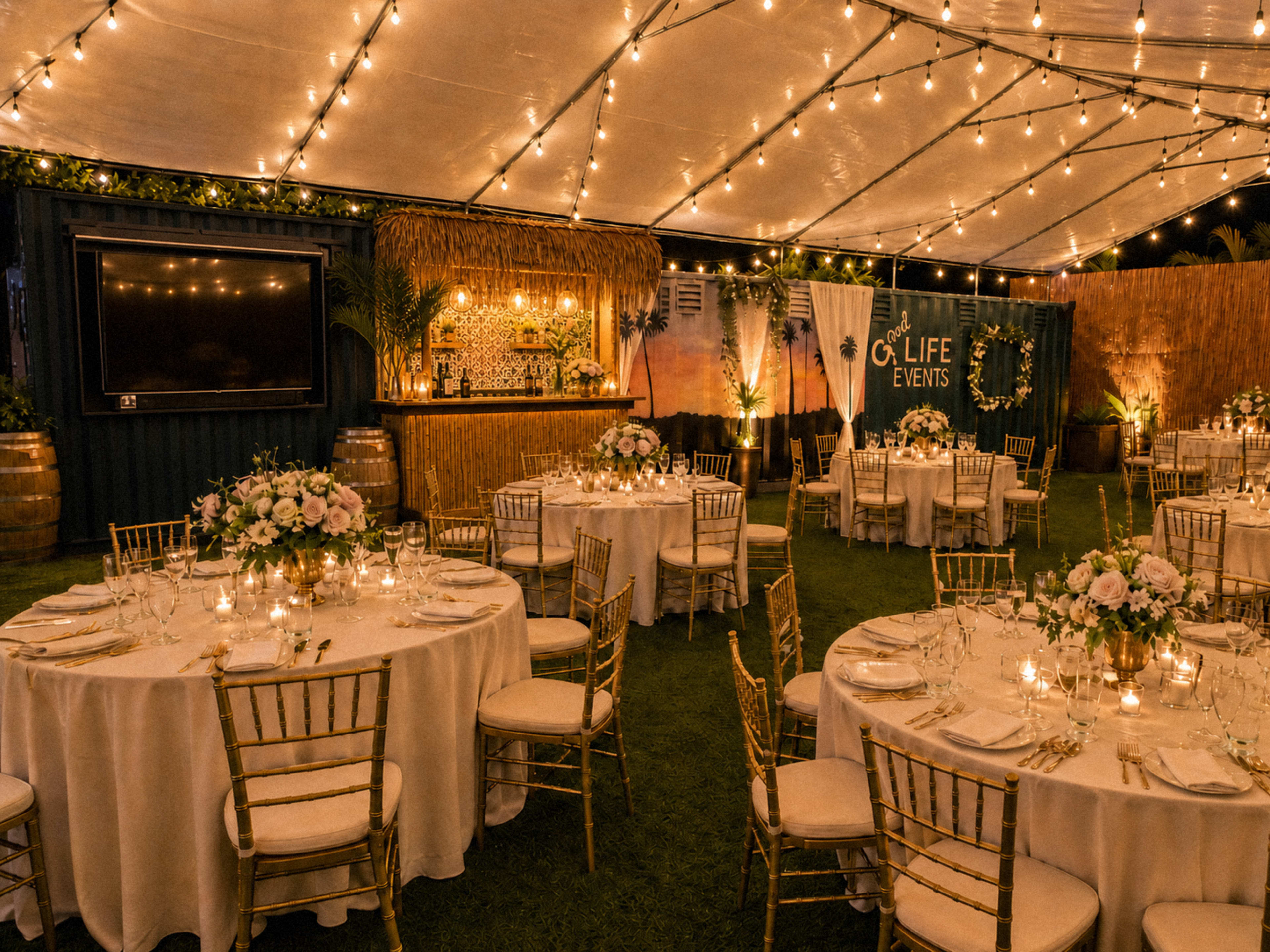 The image shows a beautifully decorated tent with round tables set for a formal event, surrounded by ambient lighting and floral centerpieces.