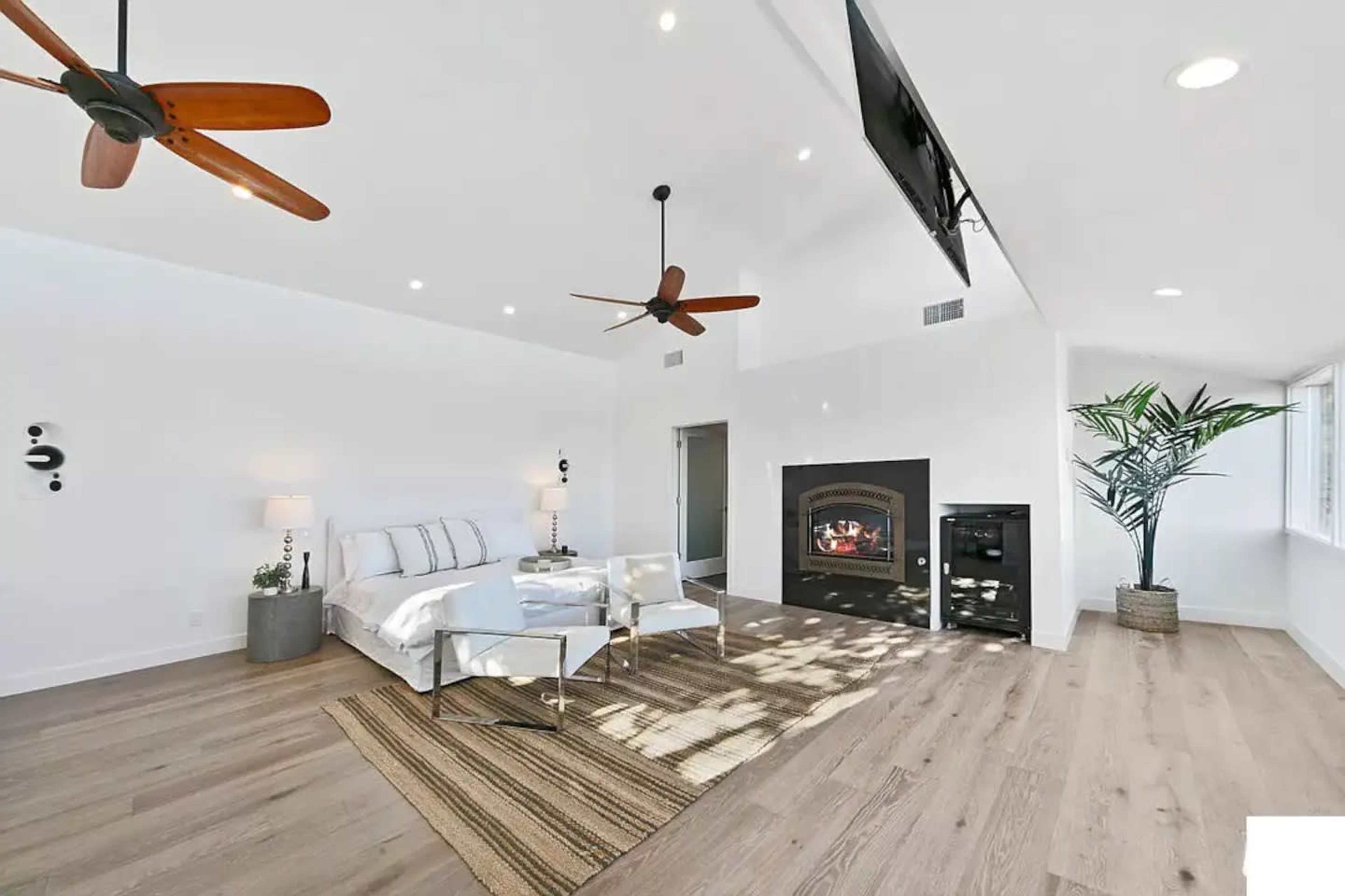 The room features a modern bedroom with a large bed, a fireplace, and large windows that allow natural light to fill the space.