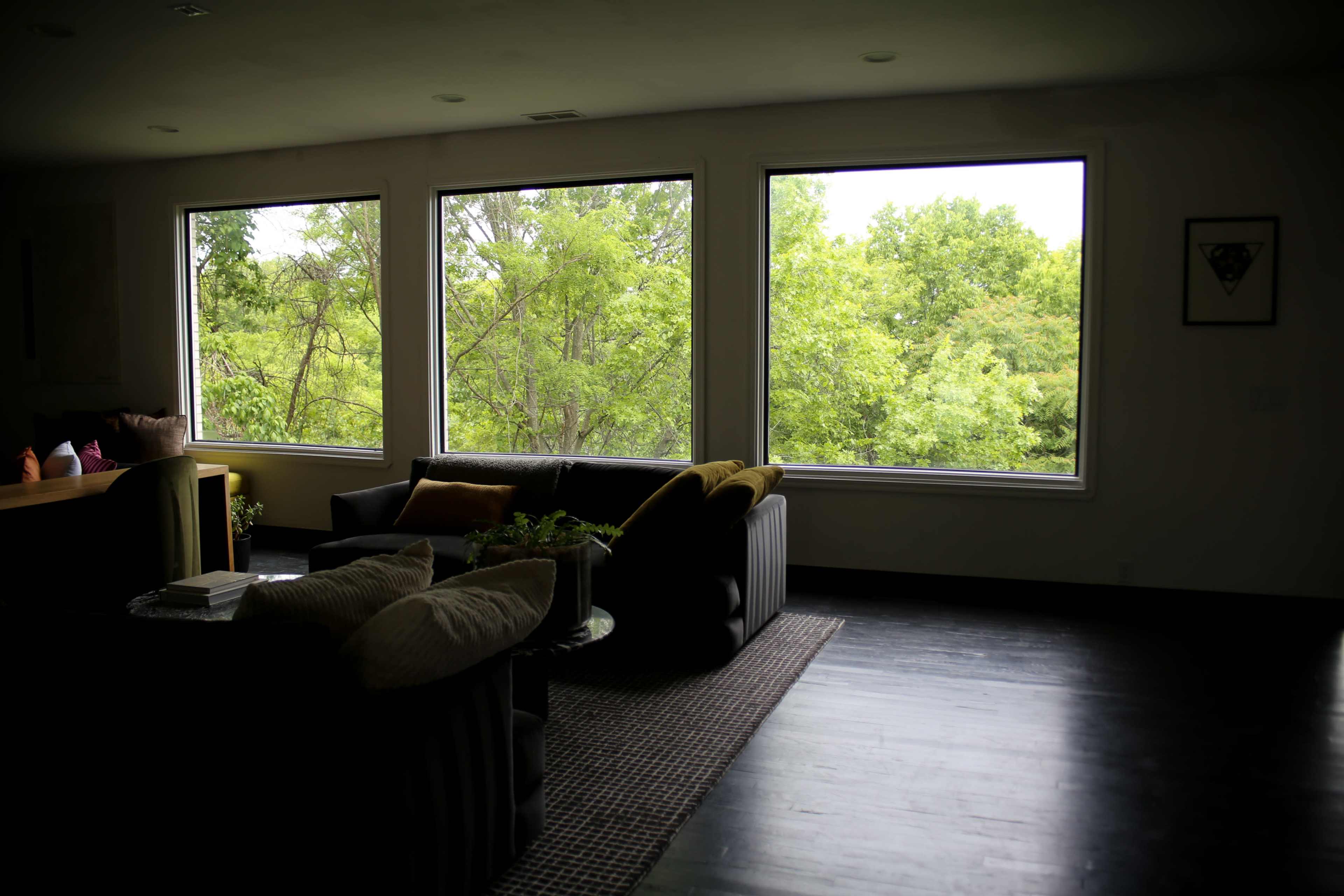 A modern living room features large windows that overlook a lush green landscape.