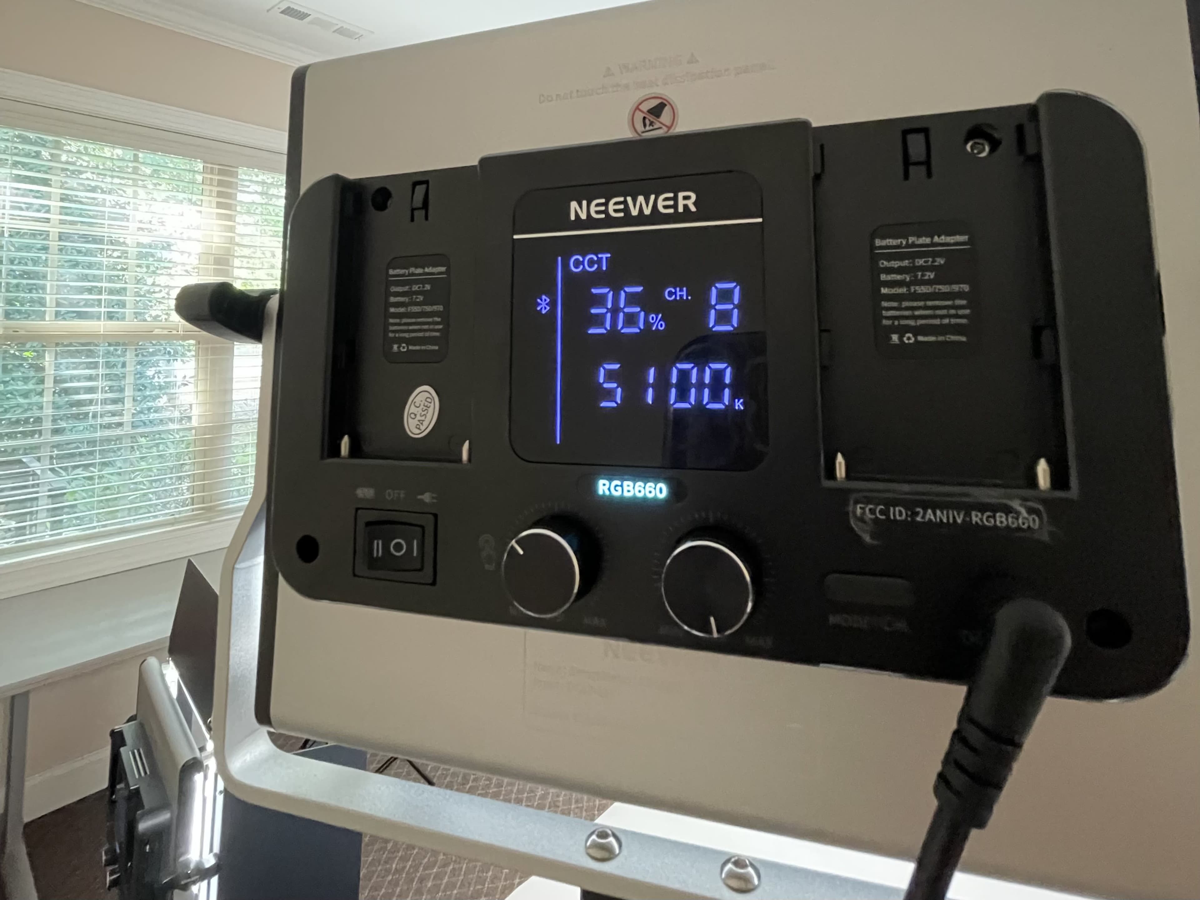 A Neewer RGB660 light control panel displaying settings for CCT, channel, and brightness in a well-lit room.