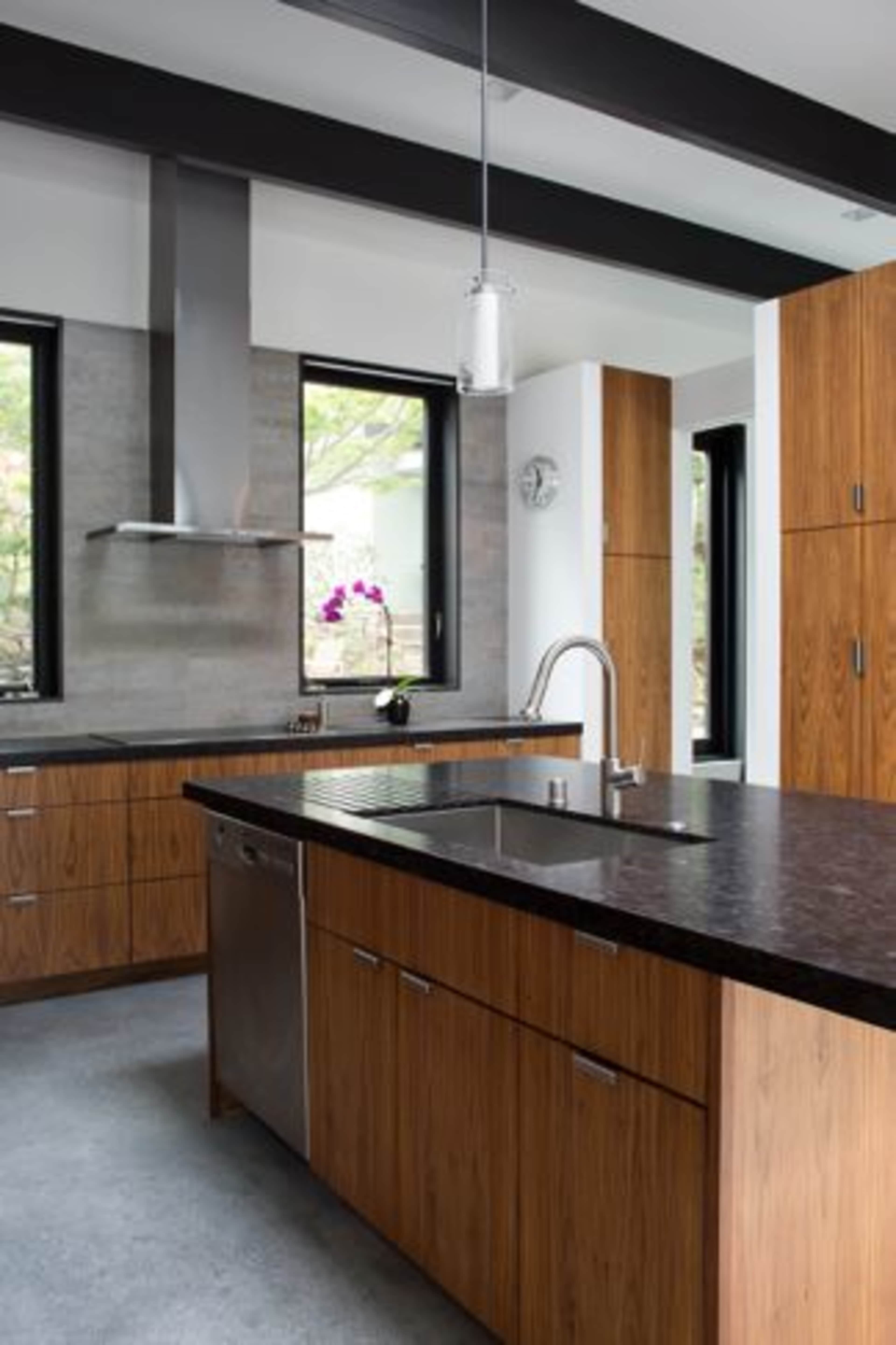A modern kitchen features wooden cabinetry, a central island with a dark countertop, and stainless steel appliances.