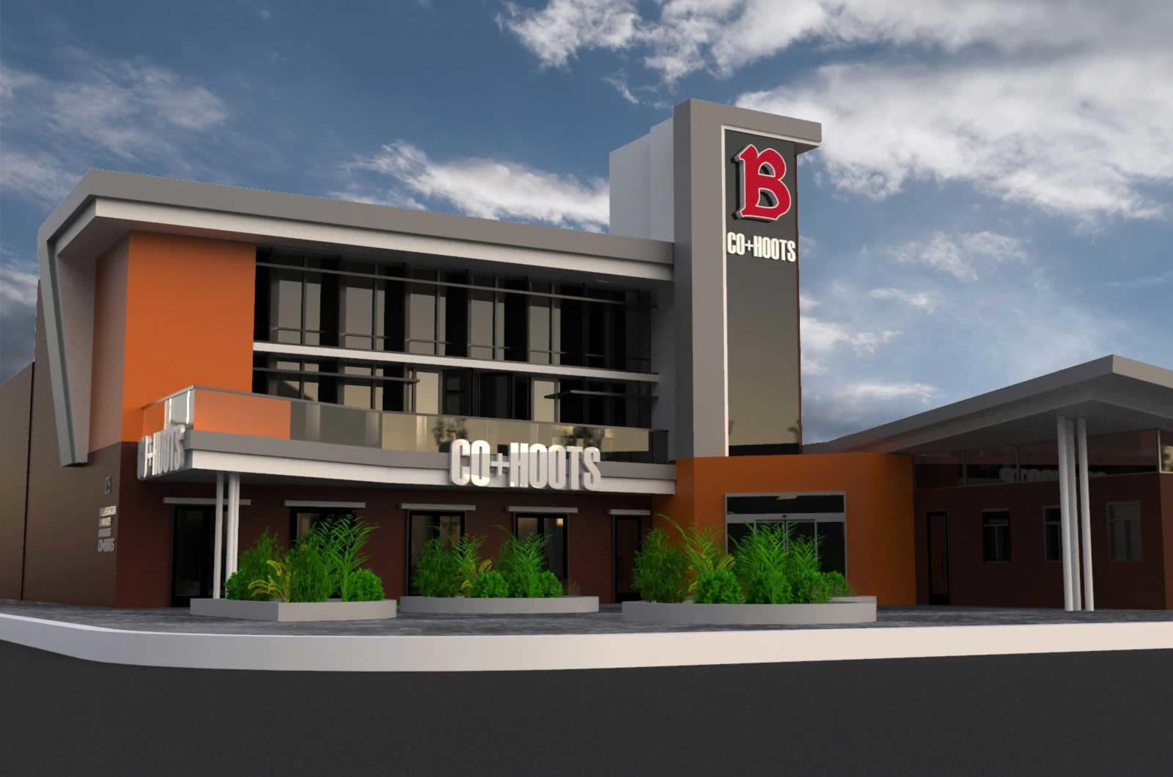 A modern building with a prominent sign reading "CO-HOOTS" and features large windows and landscaping in front.