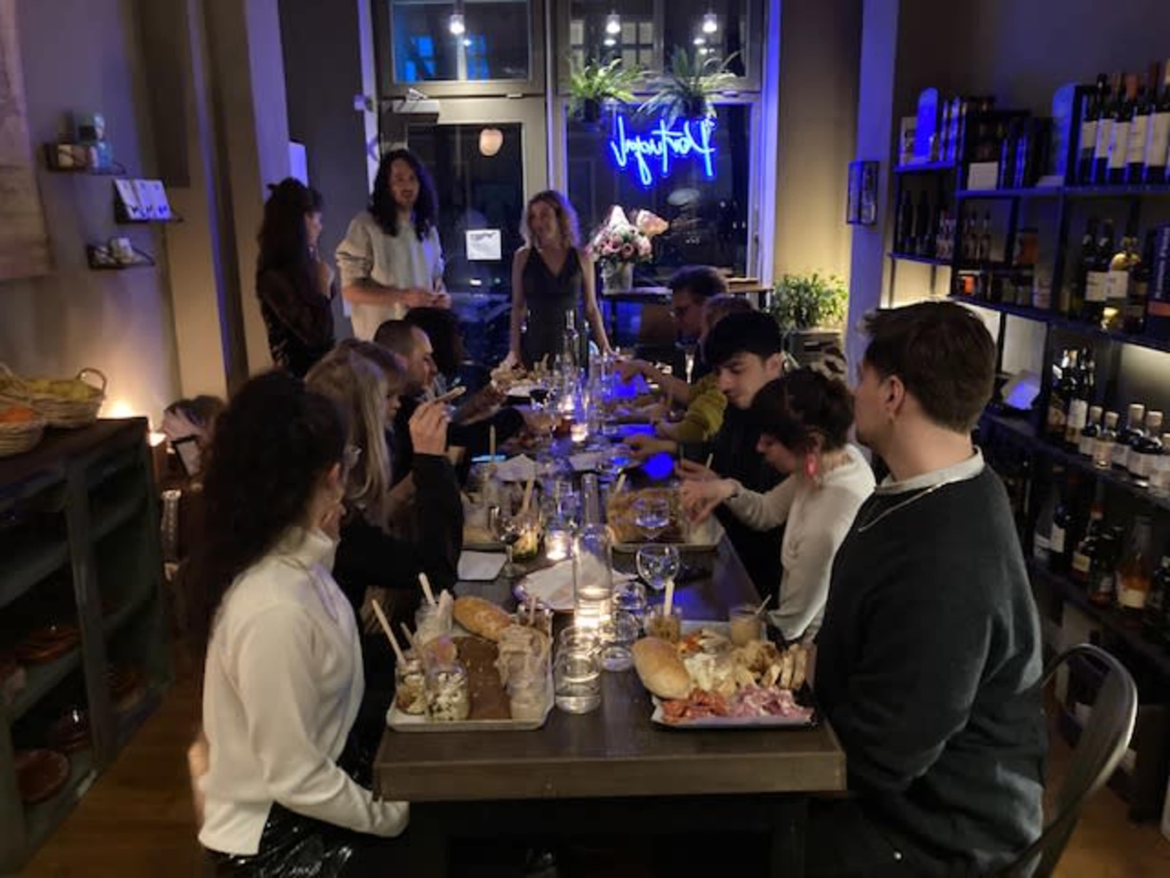 A group of people gathered around a long table filled with food and drinks in a dimly lit restaurant.