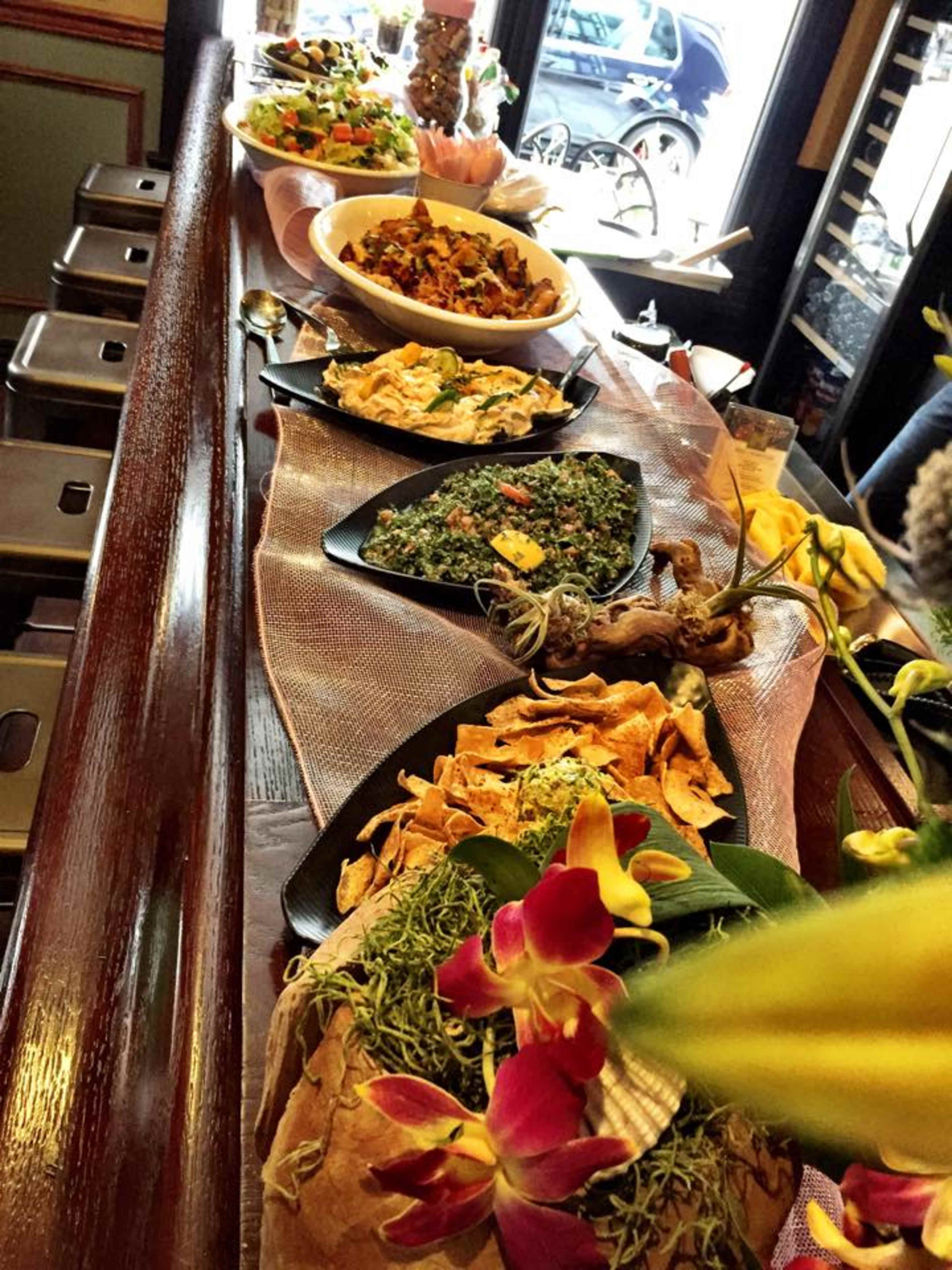 A variety of dishes, including salads and appetizers, are displayed on a wooden bar counter adorned with decorative elements.